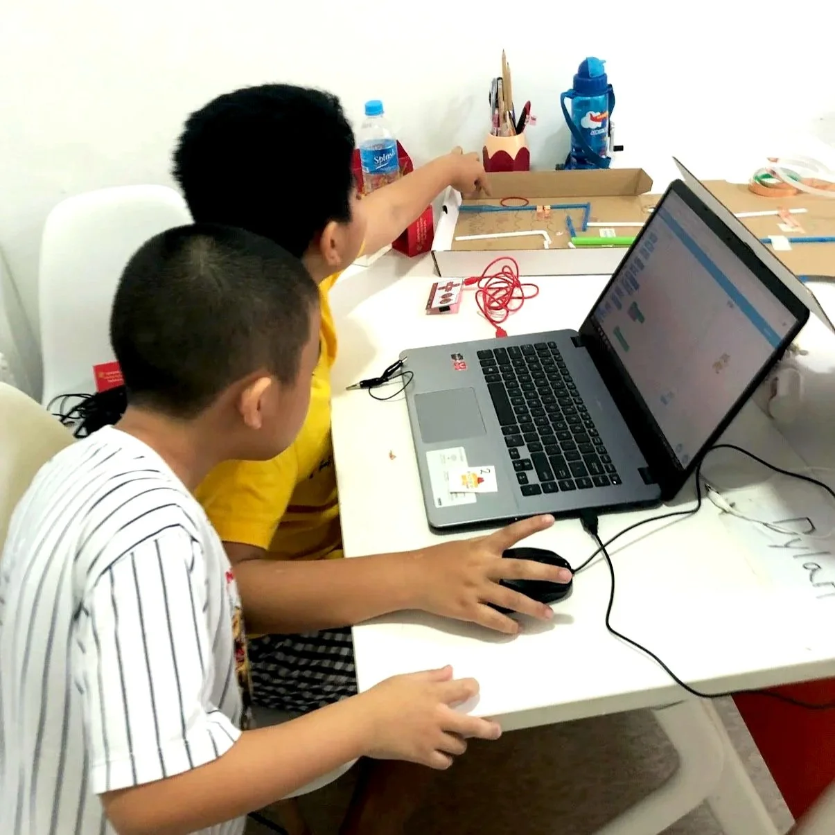 Students debugging their cardboard maze sound effect using microbit