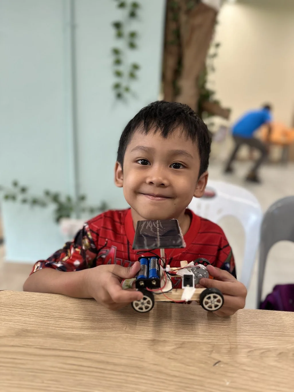 Young boy holding a hand-built solar-powered car made during an EcoVenturers renewable energy activity