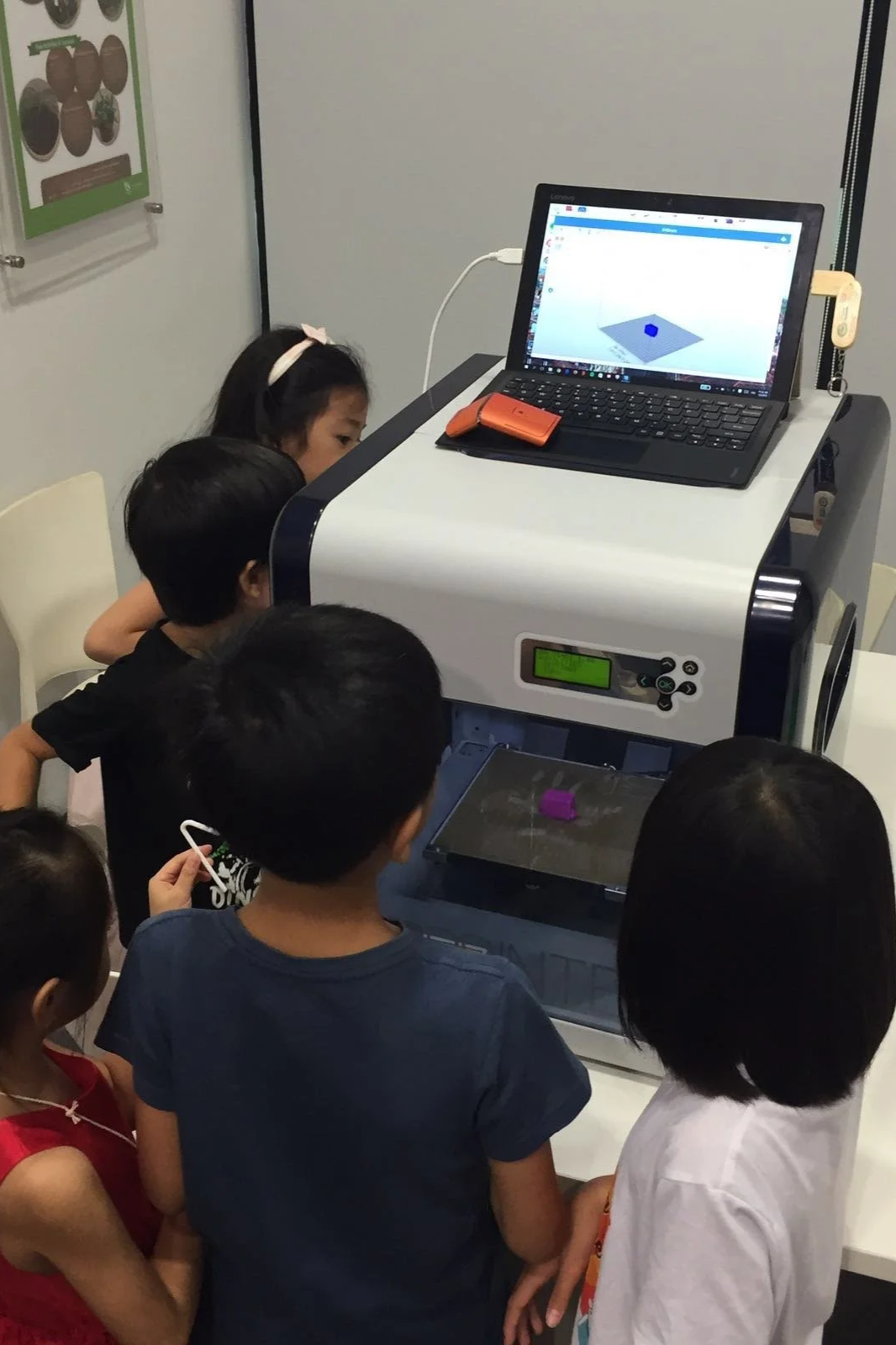 Children observing a 3D printer during a digital technology and design workshop