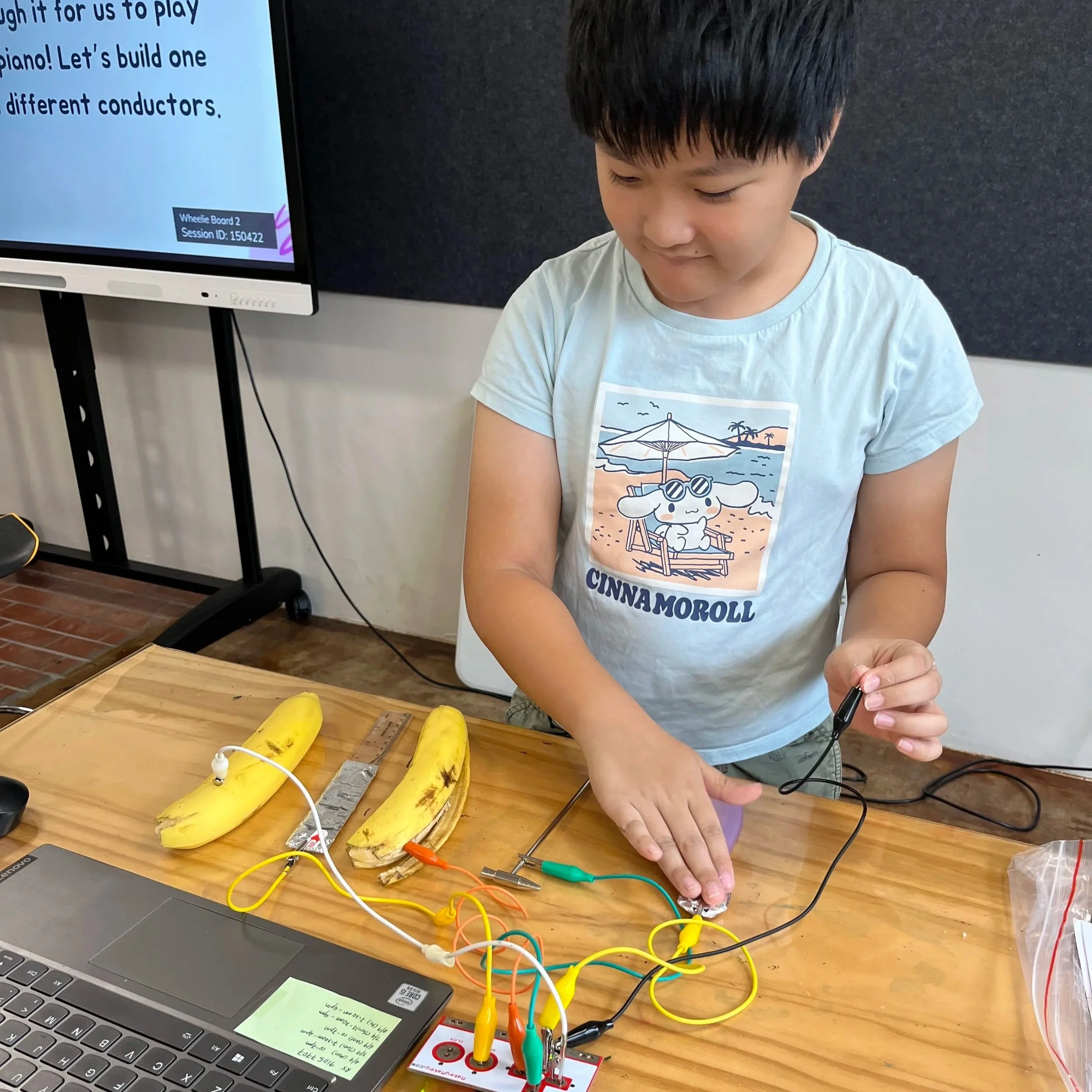 Primary school boy learning about electricity circuits and special conductors during a STEM Science of Music workshop.
