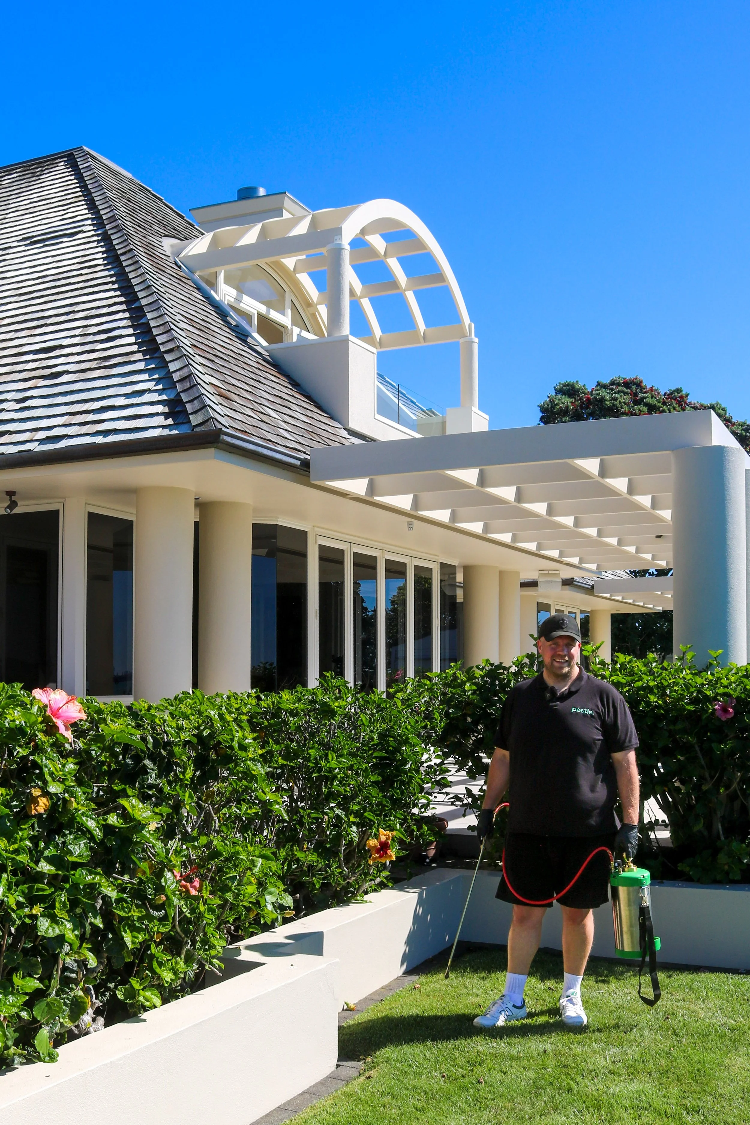 Pestie technician carrying out exterior residential pest control treatment in Auckland