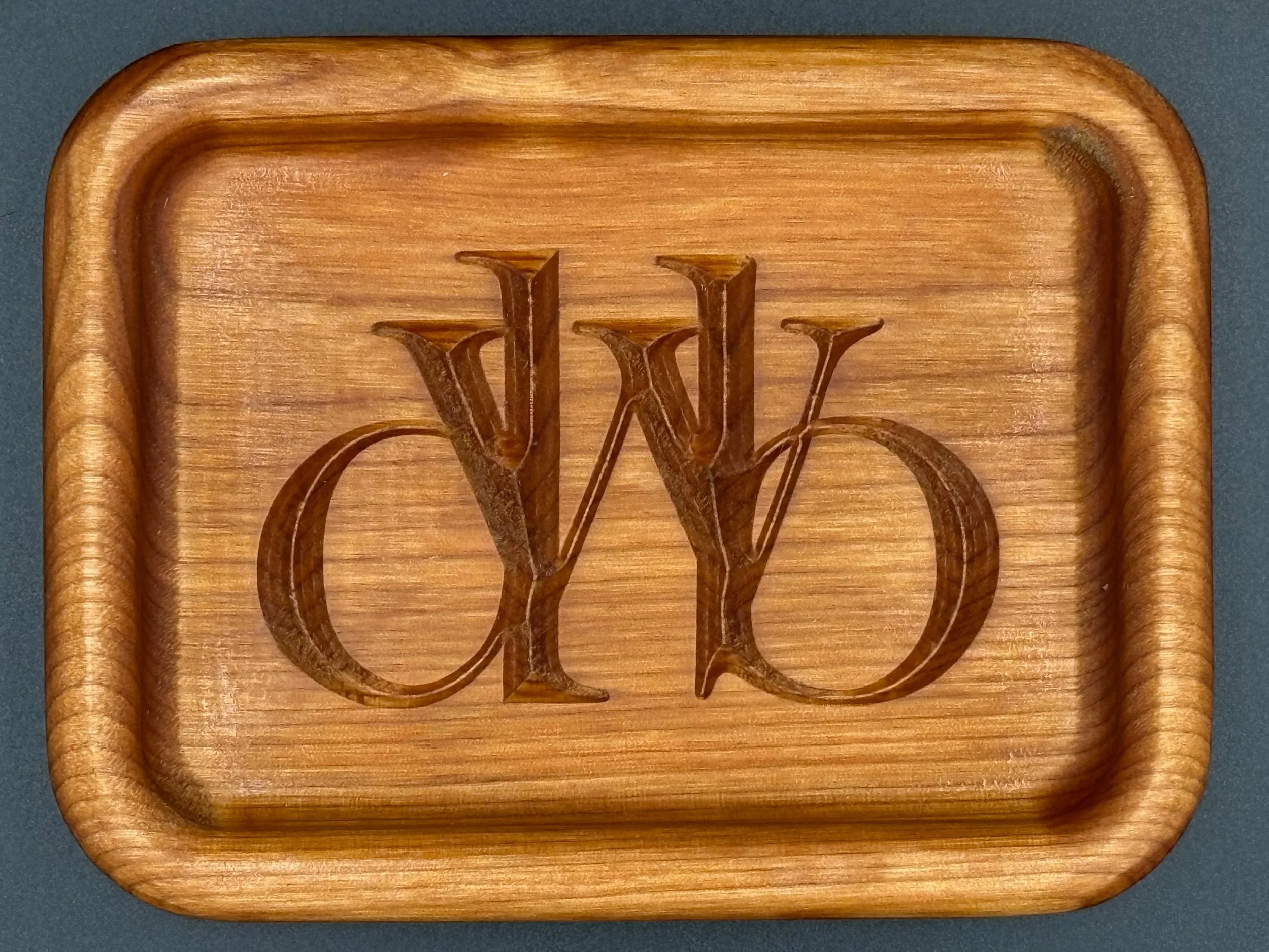 Wooden tray with an engraved intertwined 'W' and 'V' in the center.