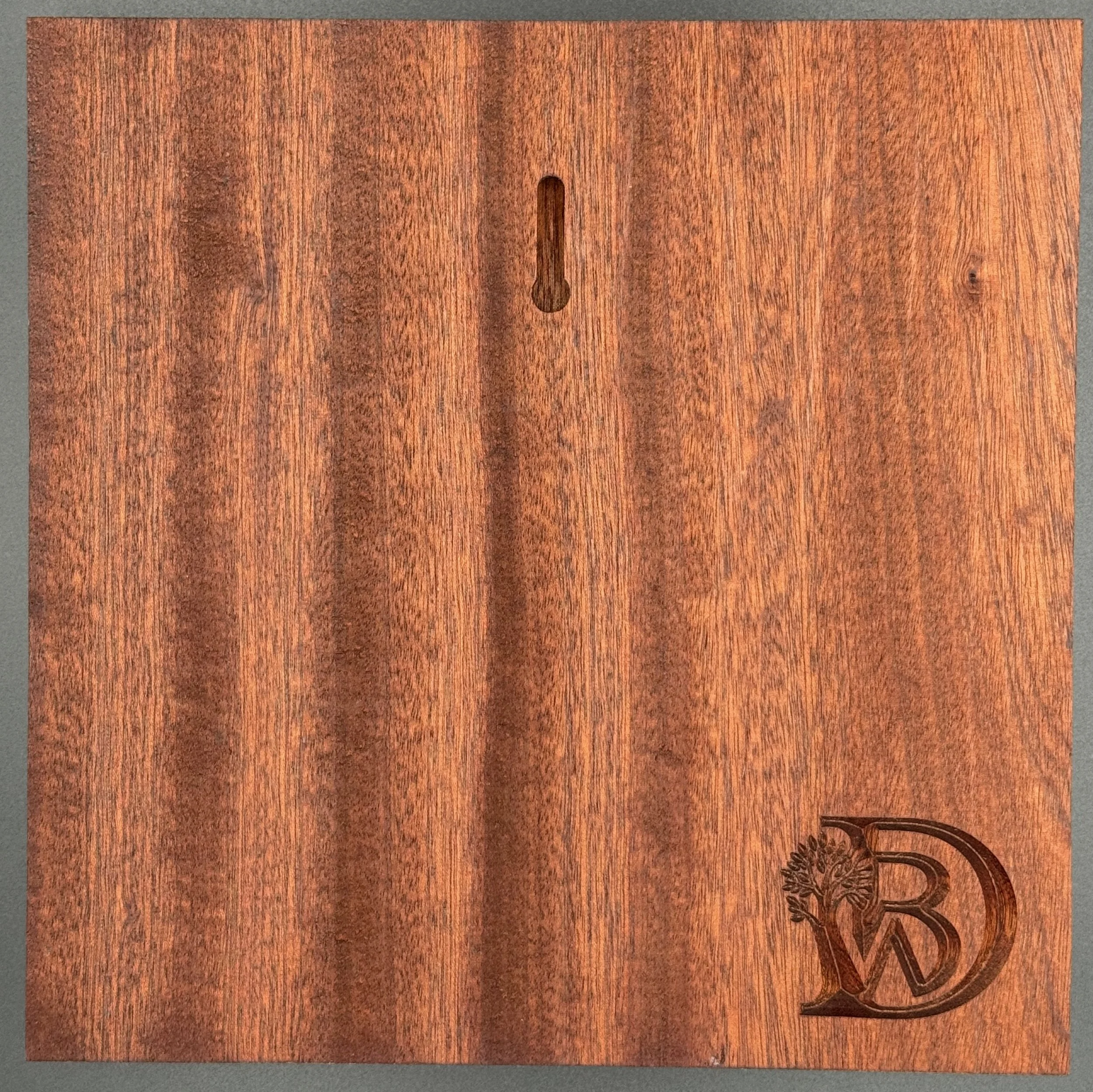 A wooden surface with a small keyhole and a logo with the letters 'WD' and a tree branch design.