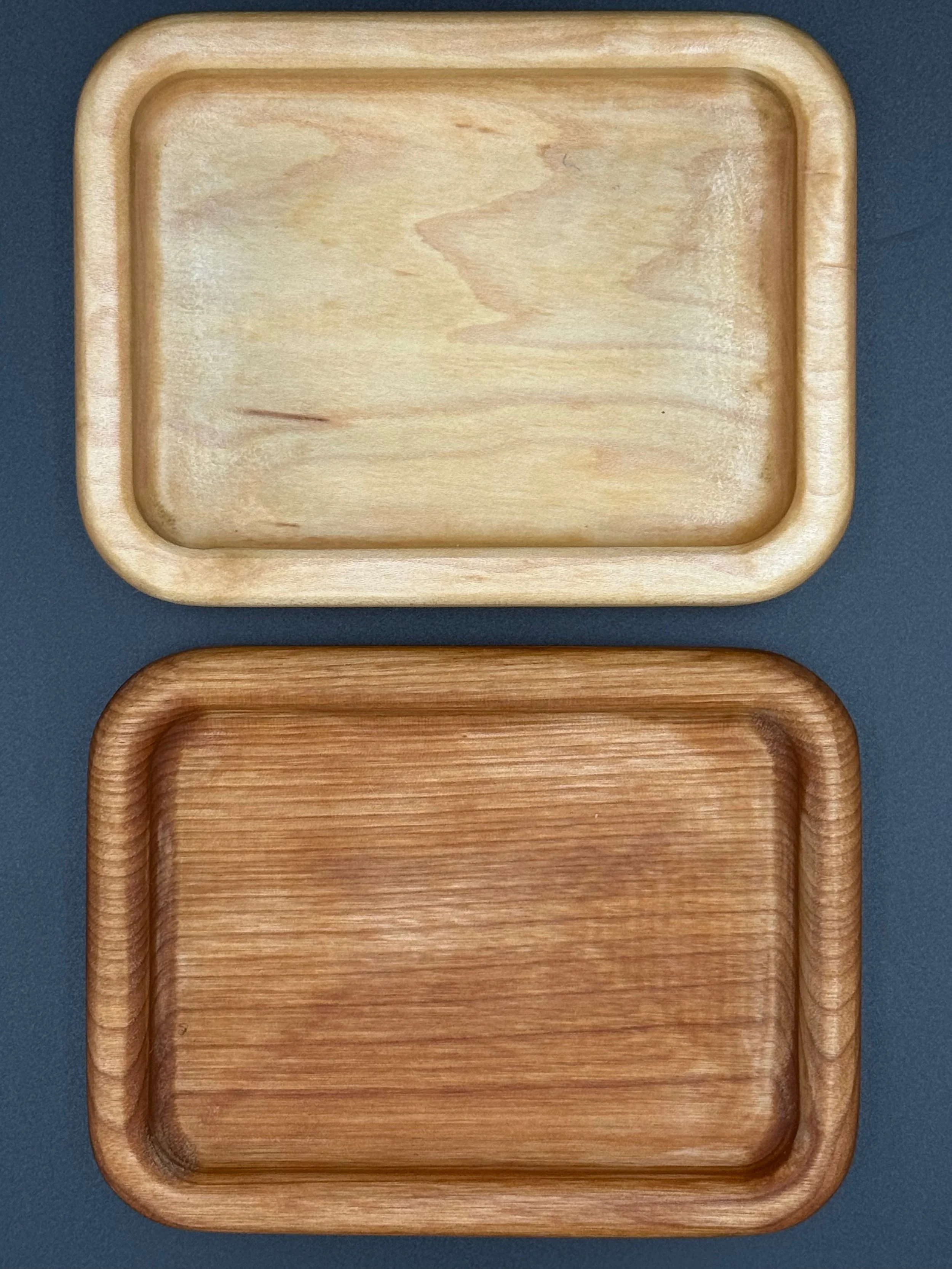 Two wooden rectangular trays, one light-colored and one darker, placed on a dark surface.