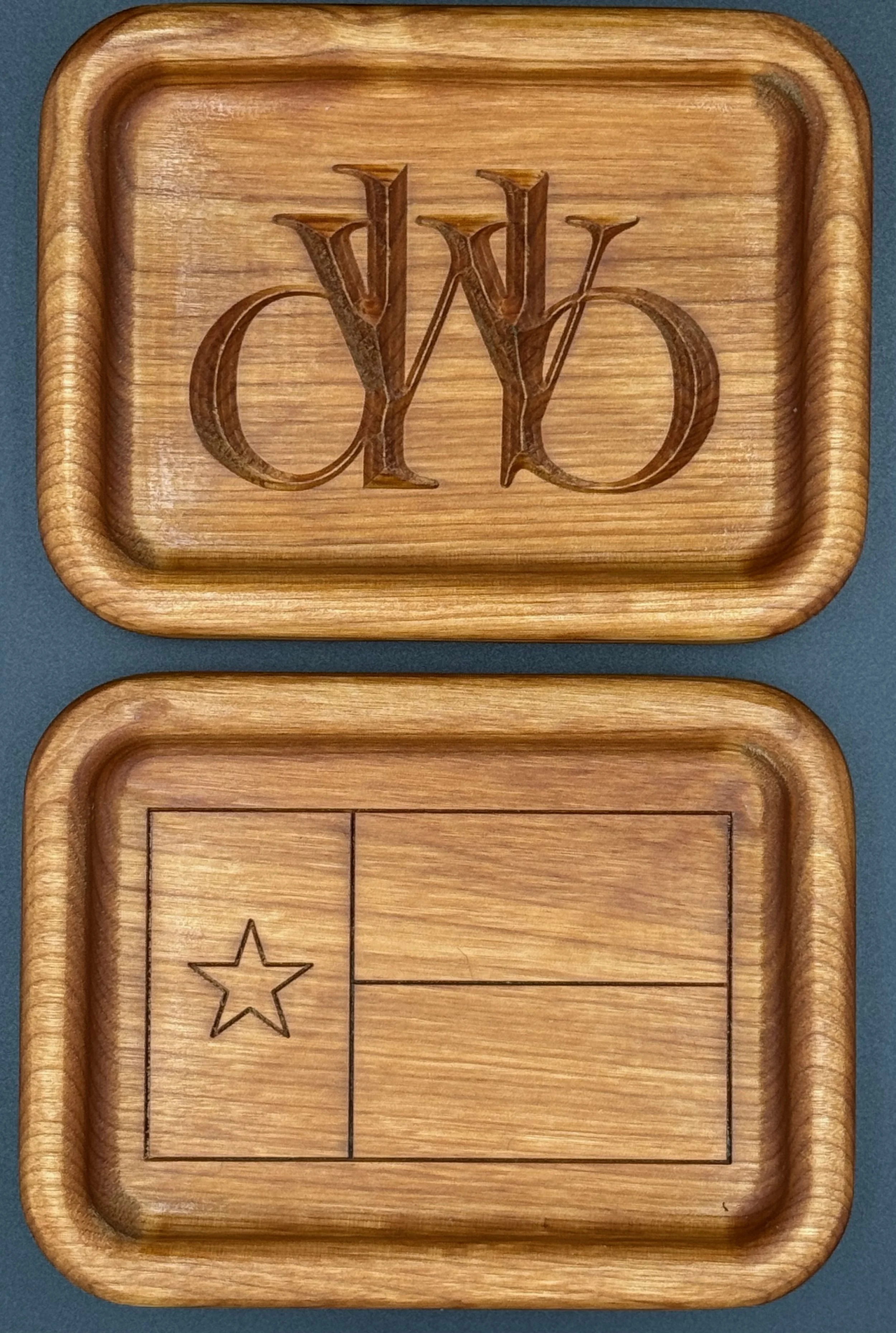 Two wooden boxes with carved and engraved designs, one with the intertwined letters 'W' and 'O' and the other with a star and rectangular sections.
