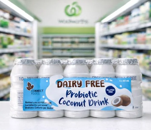 Six cans of dairy-free probiotic coconut drink on a store shelf.