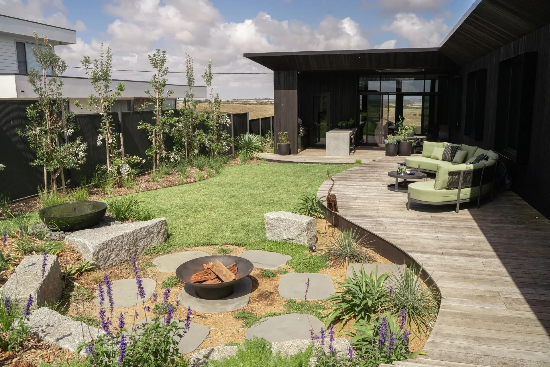 Fireplace with greenery, decking and ocean views.