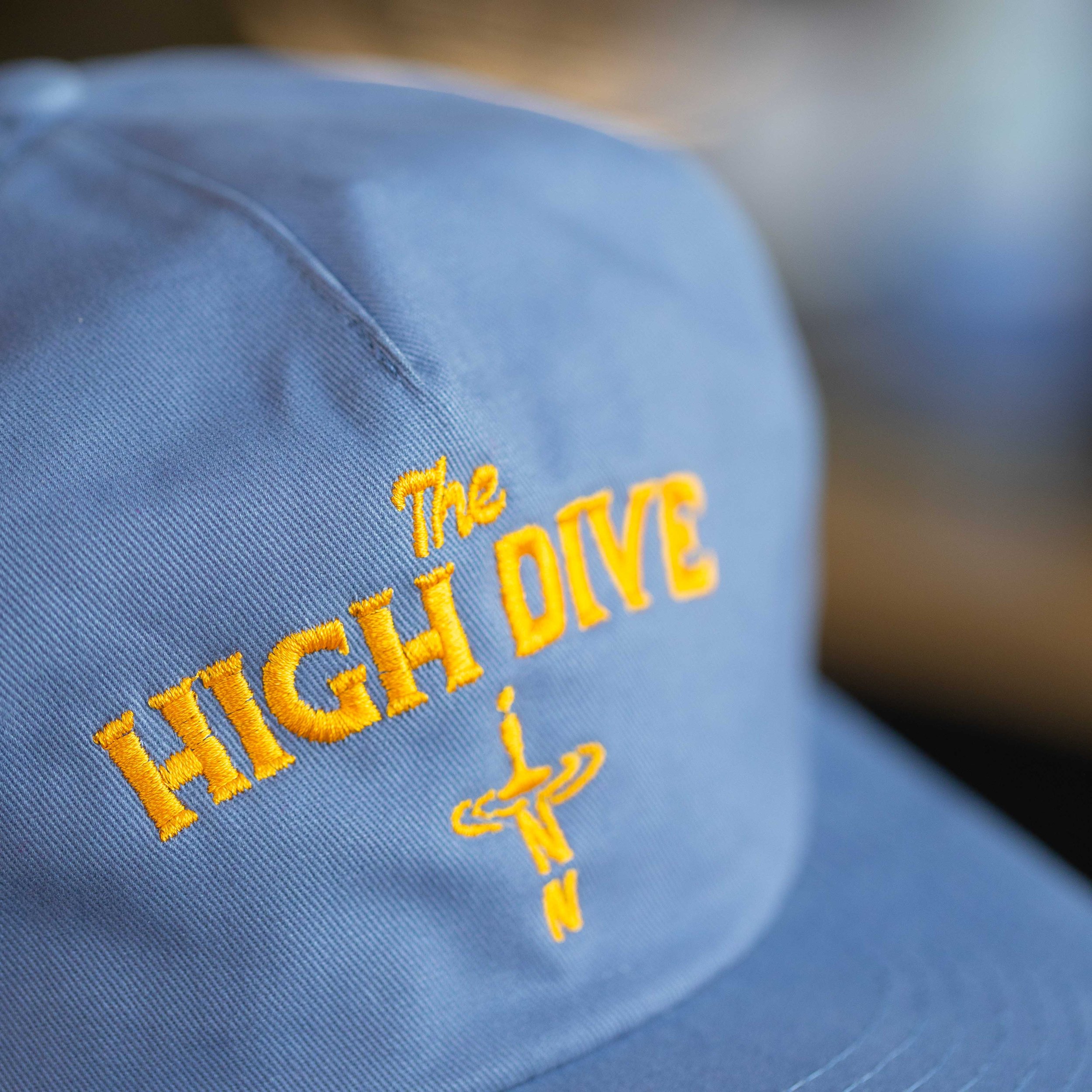 A light blue baseball cap with embroidery that says "The HIGH DIVE Inn"