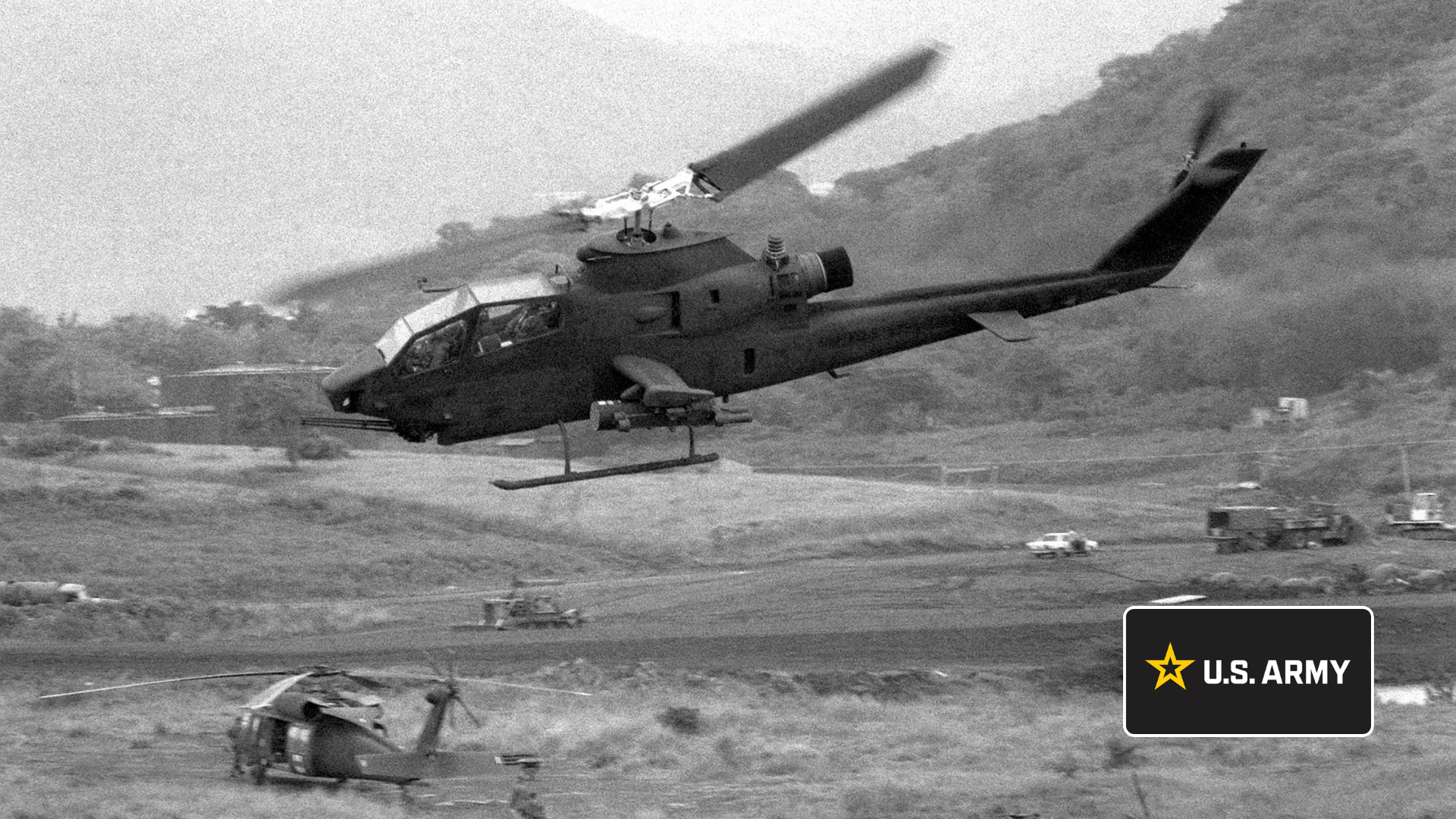 AH-1 Cobra attack helicopter flying over a field during a Vietnam-era Army operation.