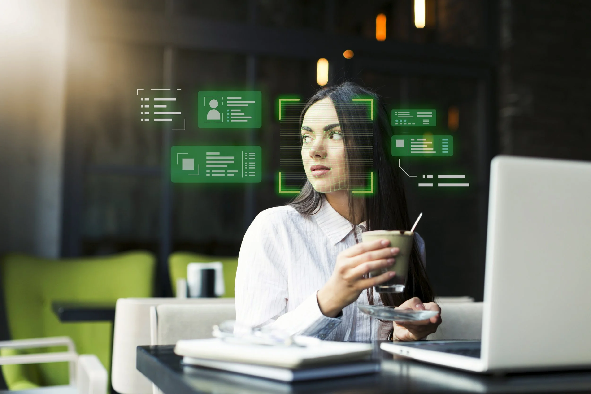 A woman using facial recognition technology on a computer at a cafe.