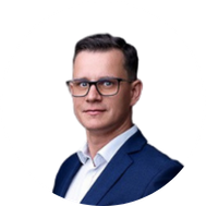 Filip Herman- Portrait of a man wearing glasses in a blue suit, white shirt, against a white background.