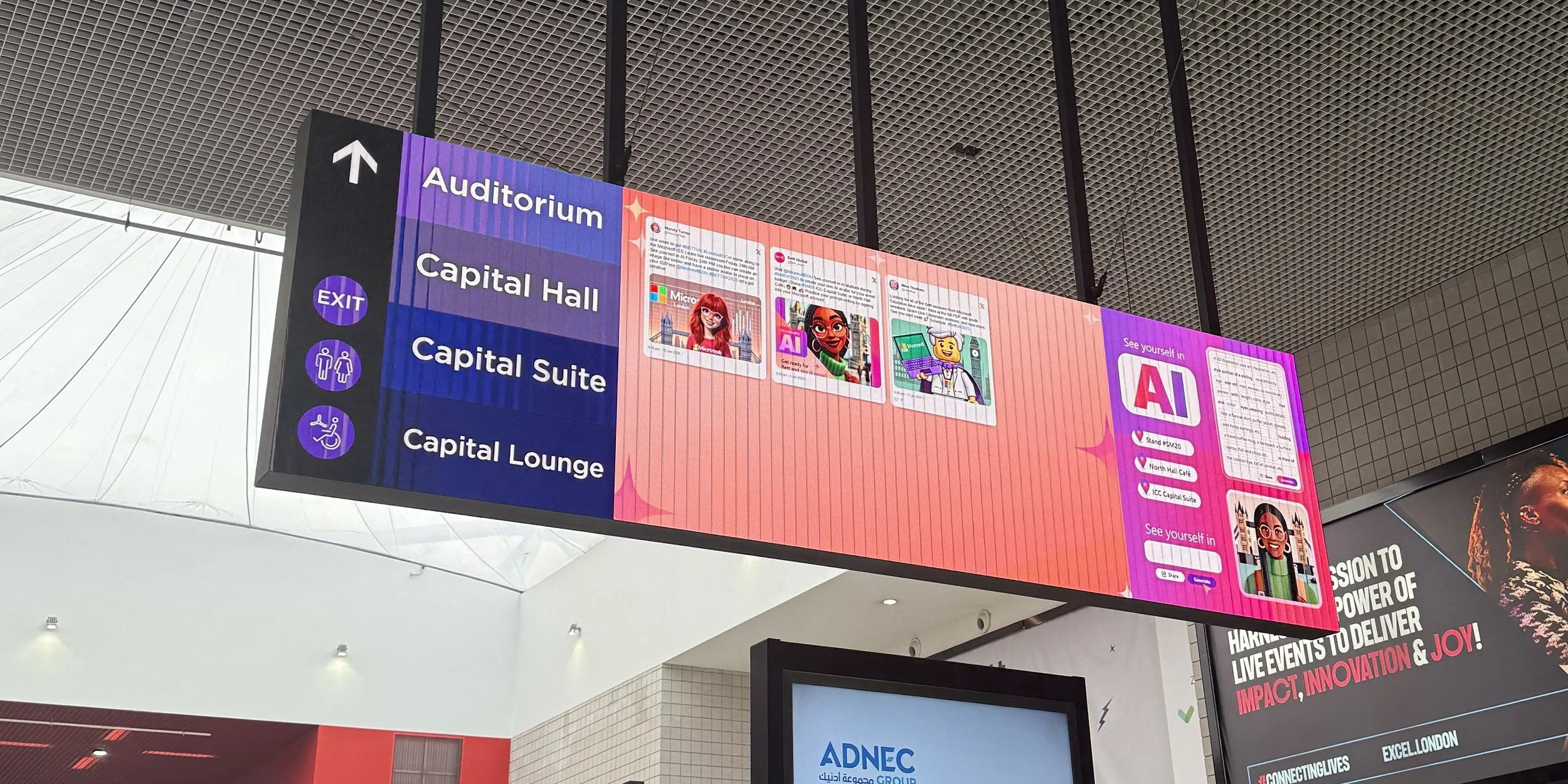 Digital directory sign showing directions to the auditorium, capital hall, capital suite, and capital lounge, with icons for exit and accessible facilities, inside a modern building.