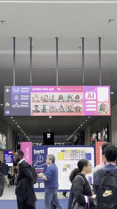 Airport terminal with directional signs and digital displays, showing family room, prayer room, and cloakroom options, with travelers walking through.