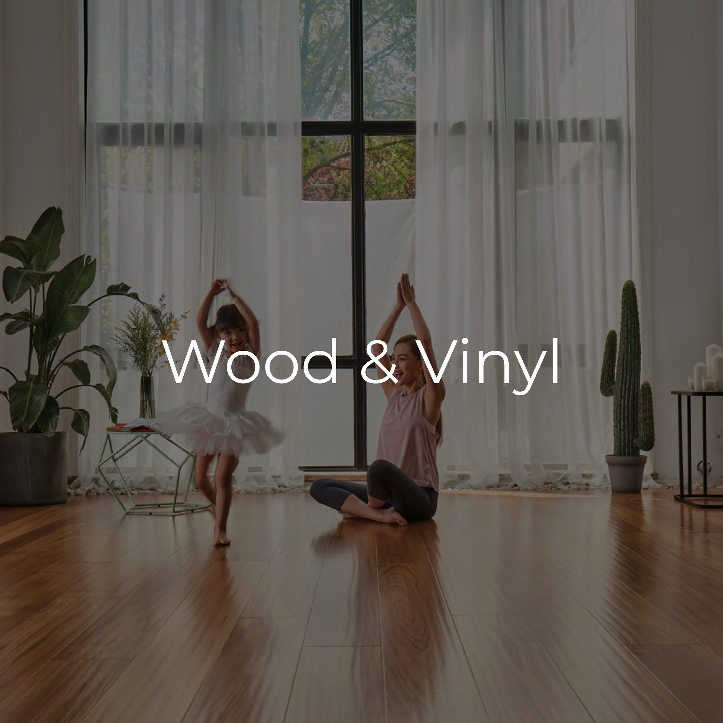 A woman and a young girl dancing and practicing yoga in a bright living room with large windows, plants, and wooden flooring. Ballet wooden flooring and vinyl tiles. 