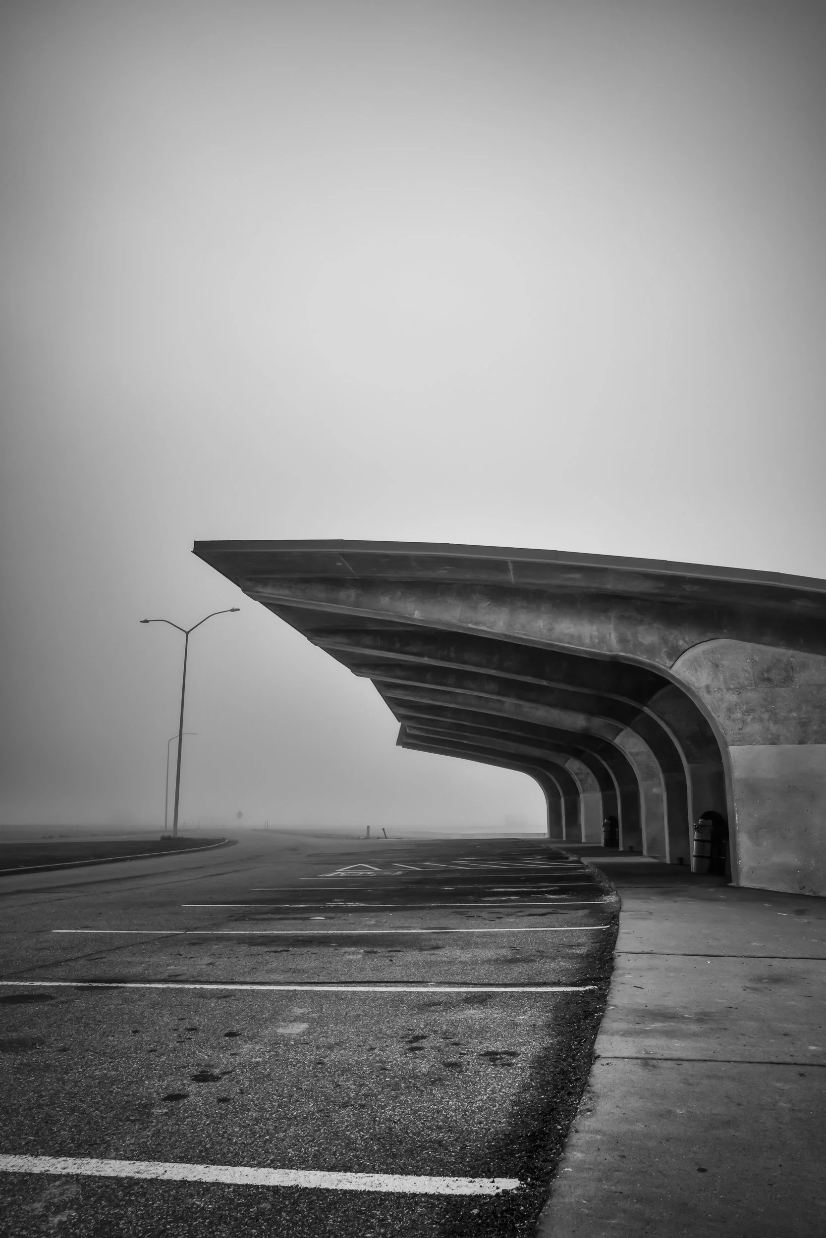 Brutalist, midcentury modern concrete parking structure off of highway enveloped in dense fog along Salt Flats, Utah.