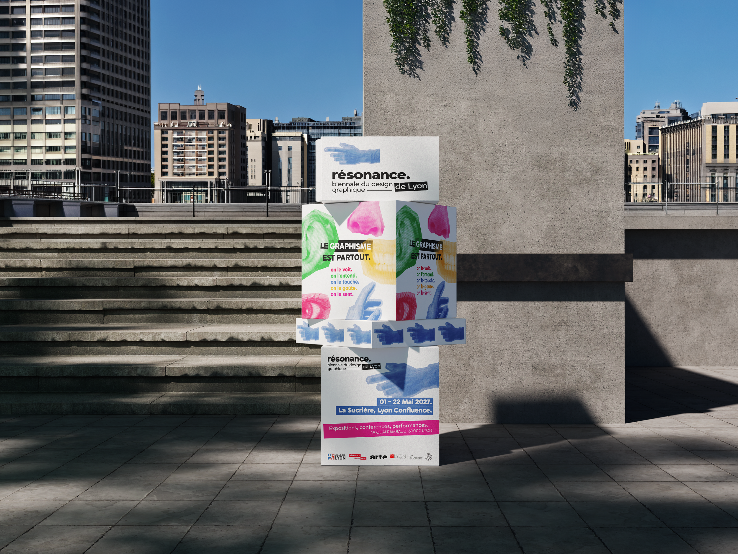 Affiche promotionnelle pour la biennale du design graphique de Lyon, se tenant du 1er au 22 mai 2027, avec des illustrations colorées de visages, de nez, de mains et de lèvres, et du texte en français sur un fond urbain avec des escaliers en pierre et des bâtiments en arrière-plan.