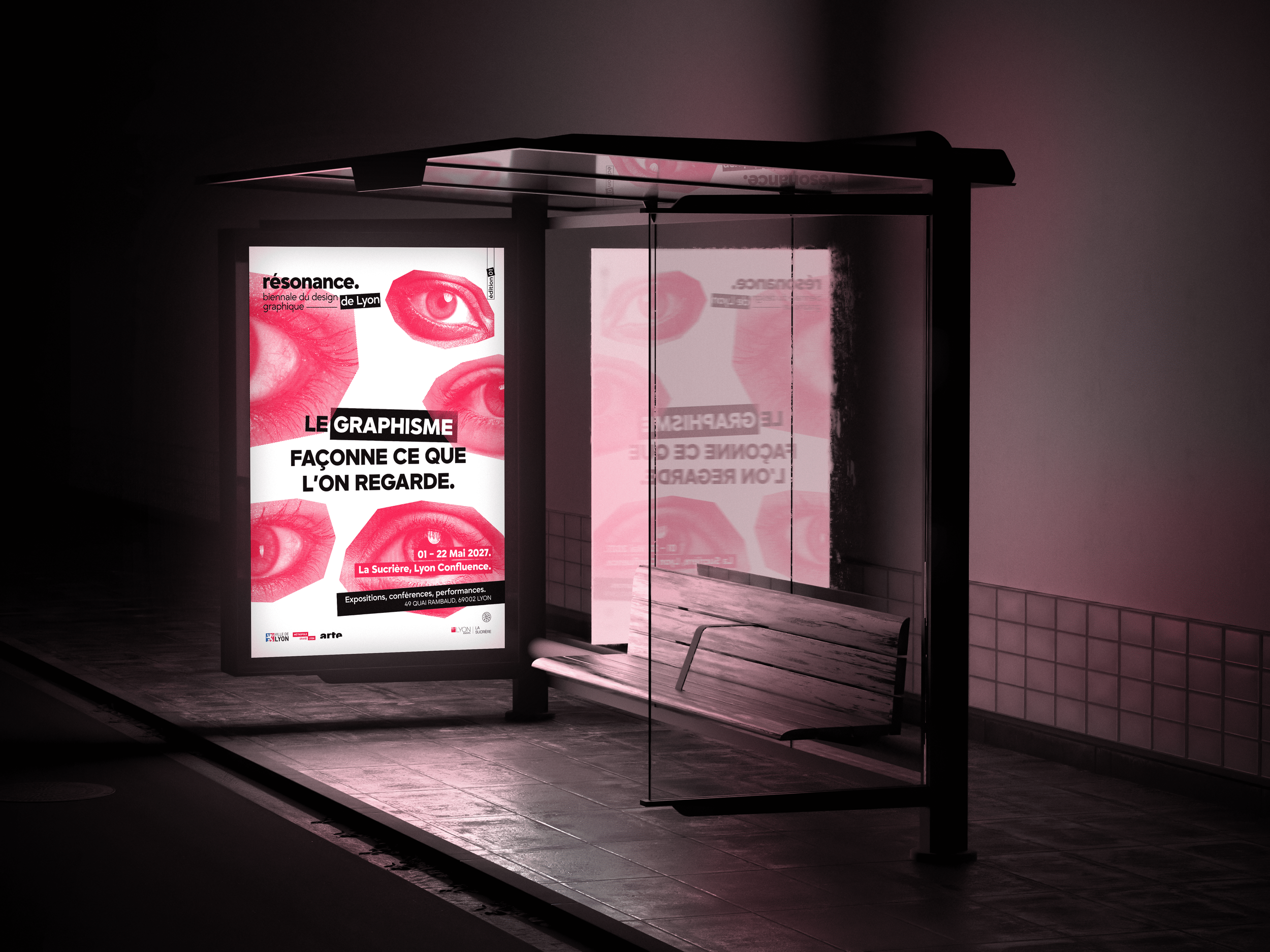 Affiche d'une exposition sur le graphisme dans un abri de bus, avec des images de yeux en rouge et noir, et du texte en français.