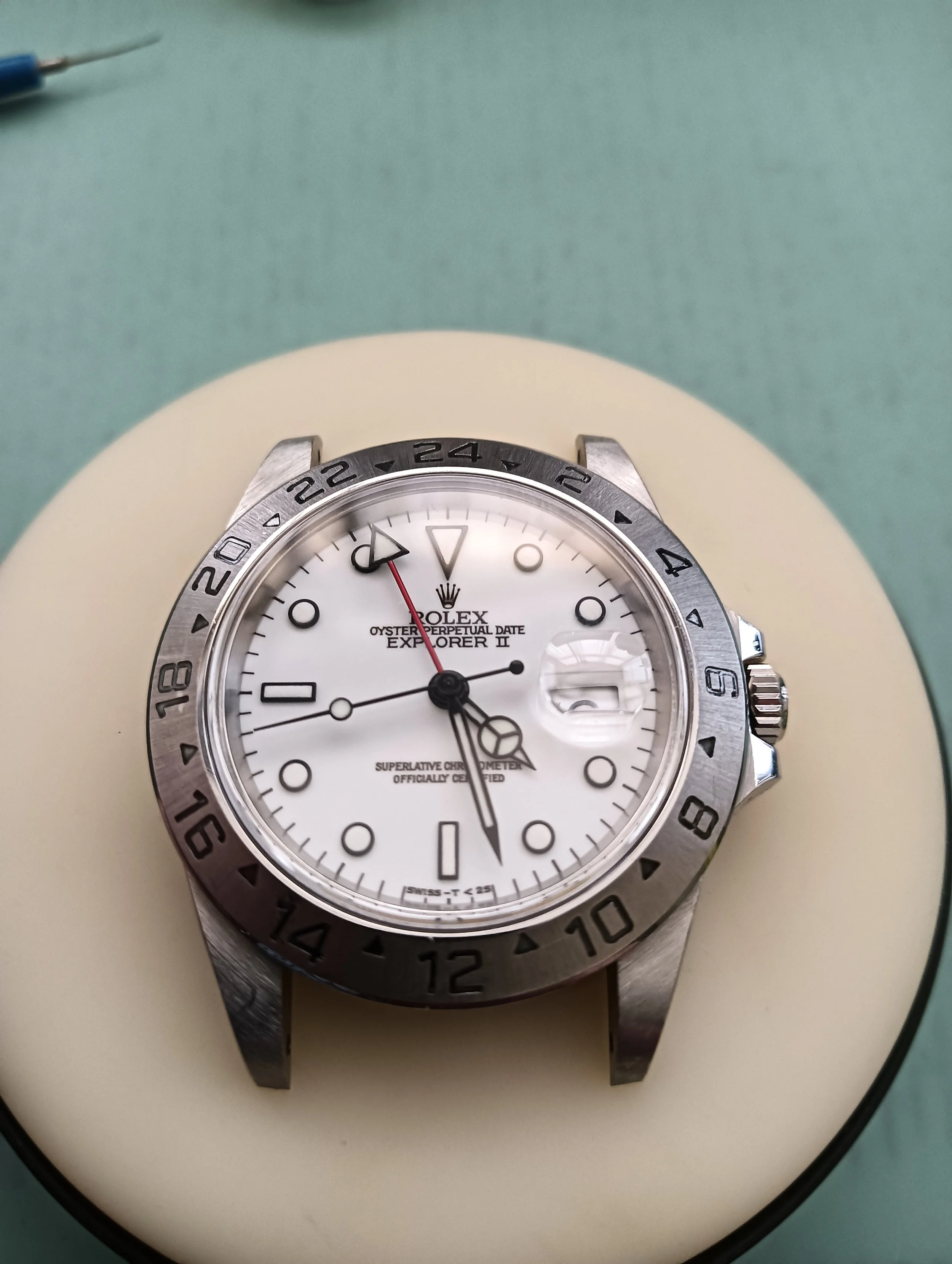 A Rolex Explorer II wristwatch with a white dial and a metal bezel, resting on a white cushion.
