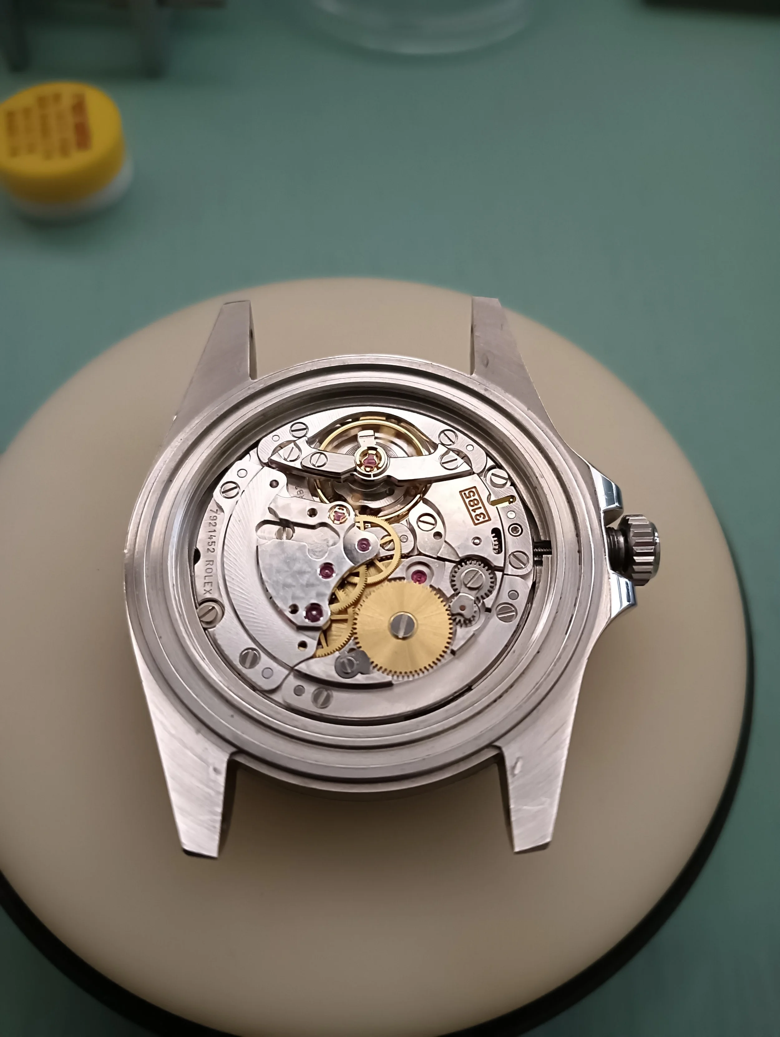 Close-up of a mechanical watch movement inside a watch case, with visible gears and intricate internal components.