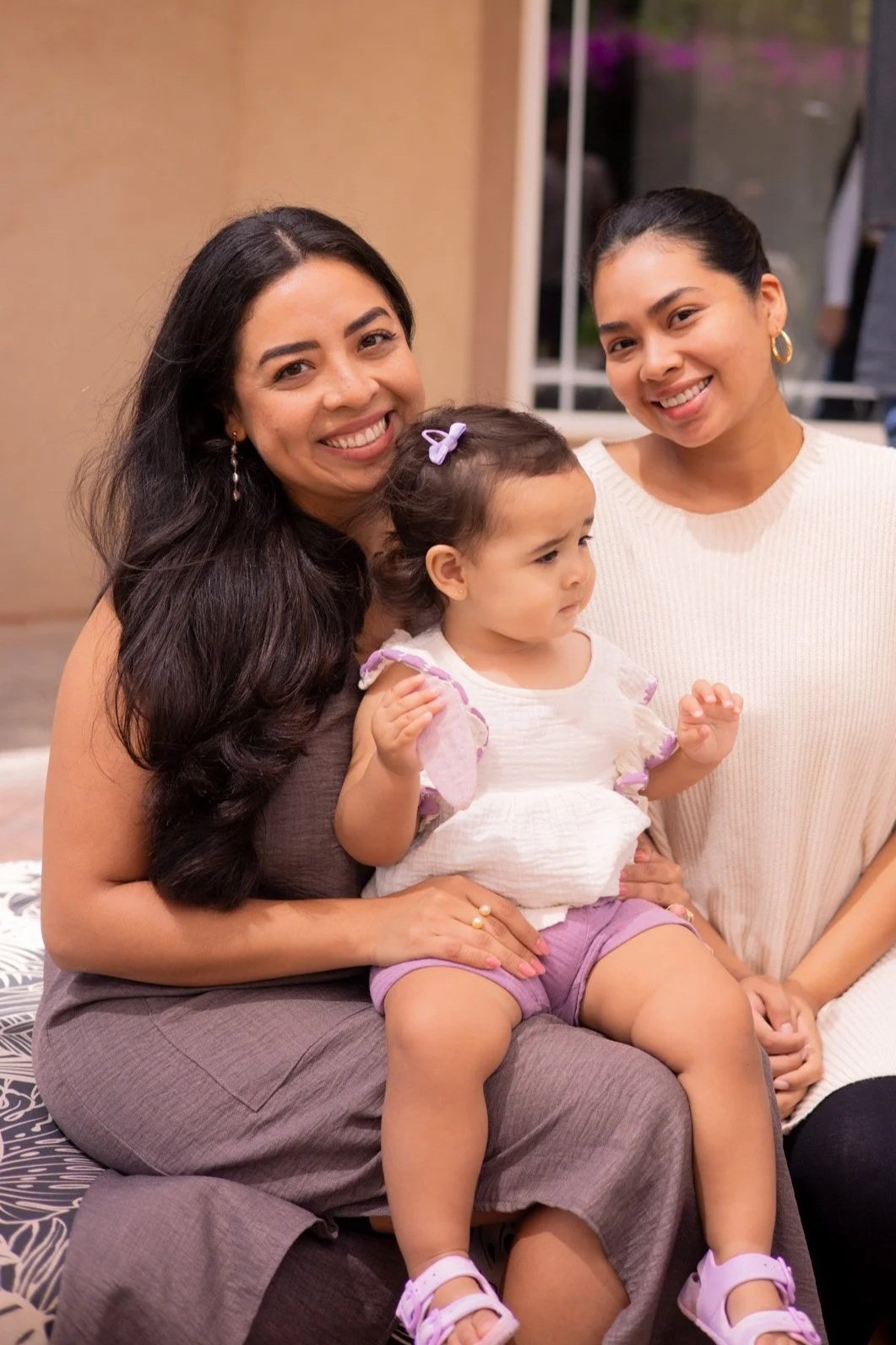 Three women and a young girl sitting together indoors, smiling and posing for the photo.