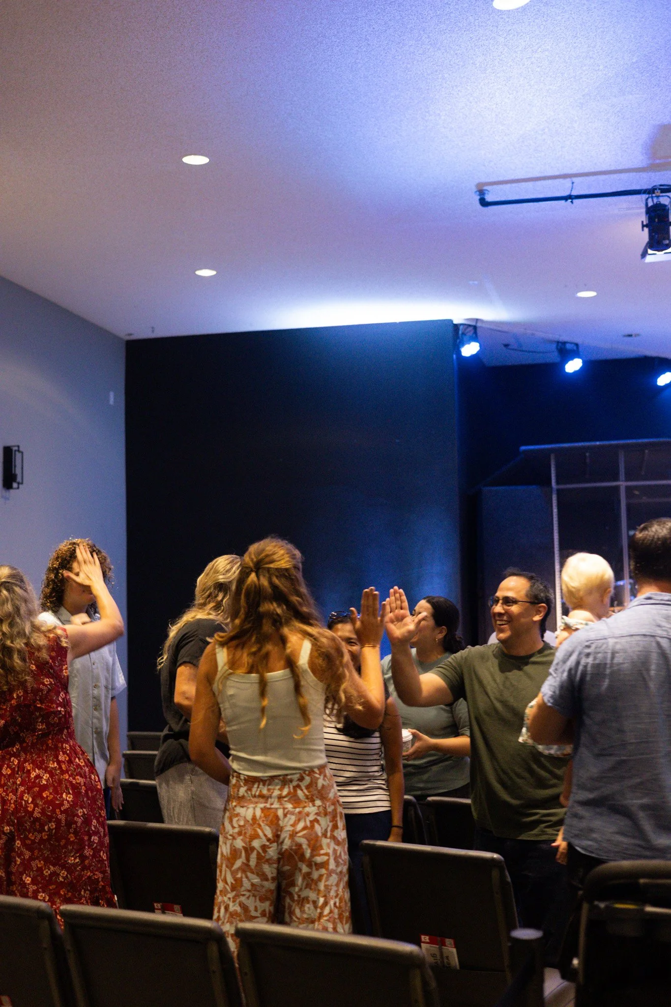 Two women smiling and holding coffee cups, standing near a large window in a modern office space.