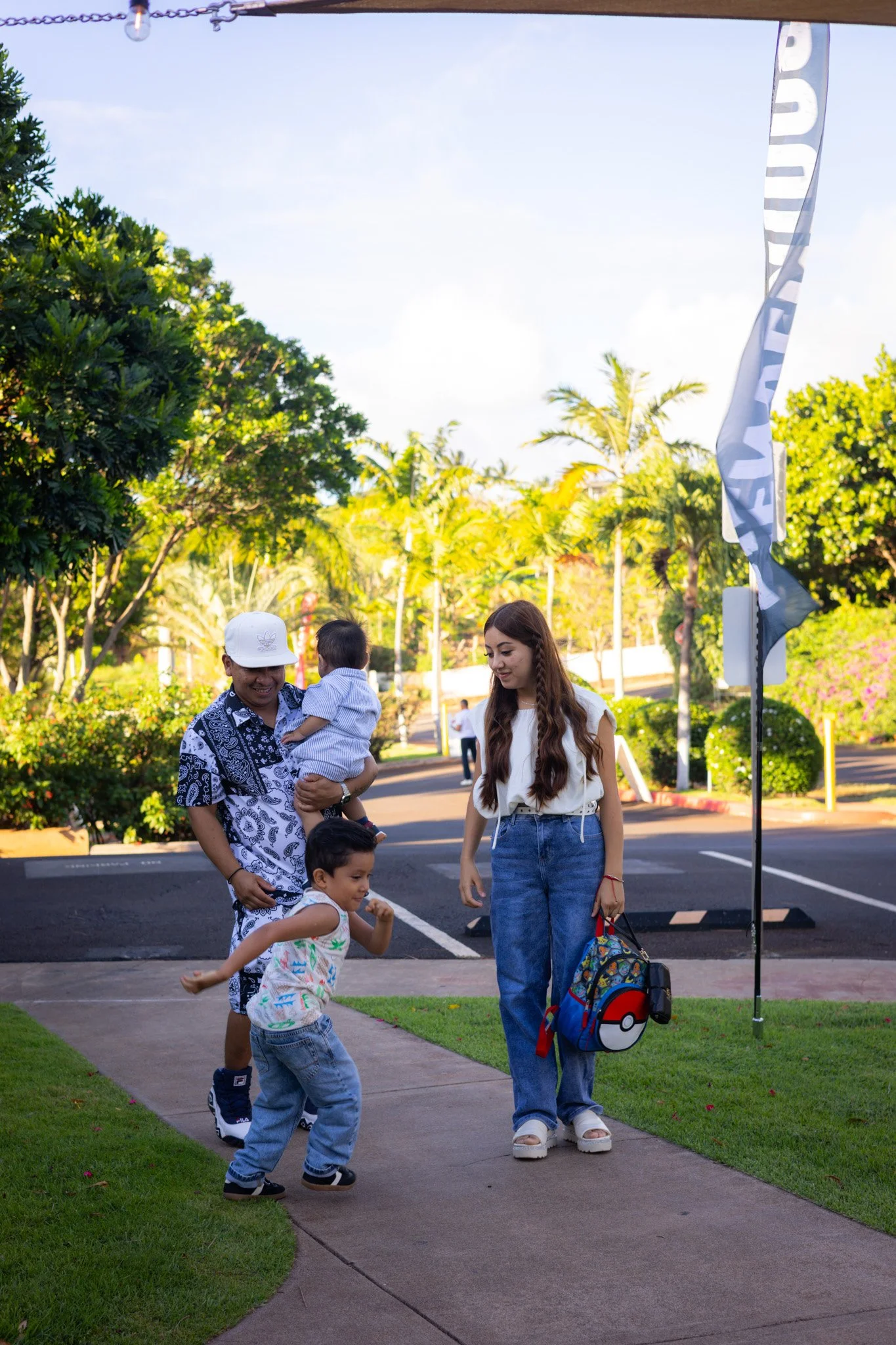 A family of three, a woman, a man, and a young boy, smiling and posing together indoors, with a colorful abstract mural in the background.
