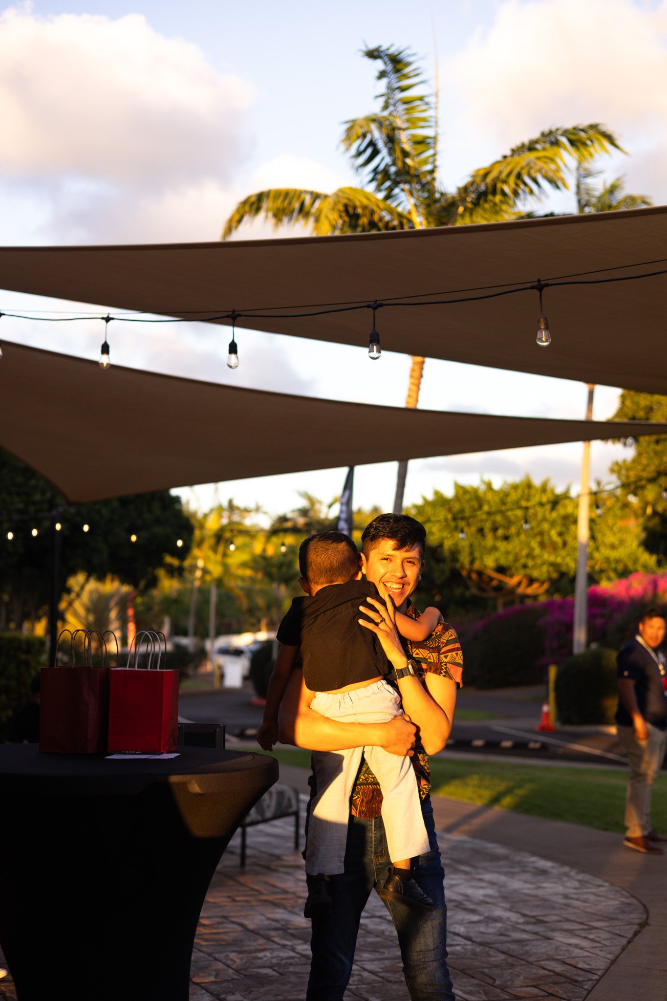 Two women smiling and holding coffee cups, standing near a large window in a modern office space.