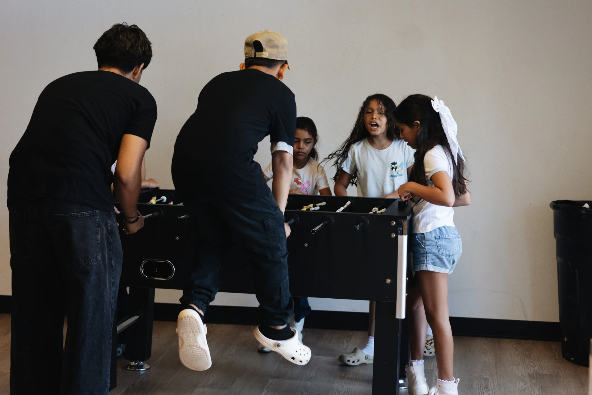 Children playing foosball together in an indoor room.