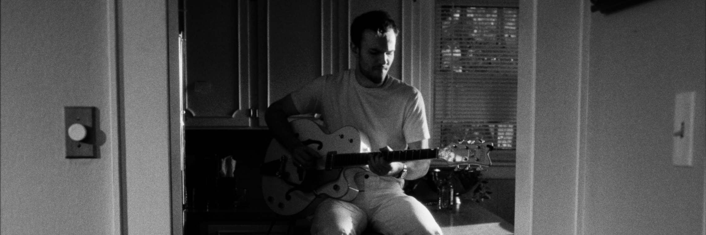 black and white music video frame of a man playing electric guitar