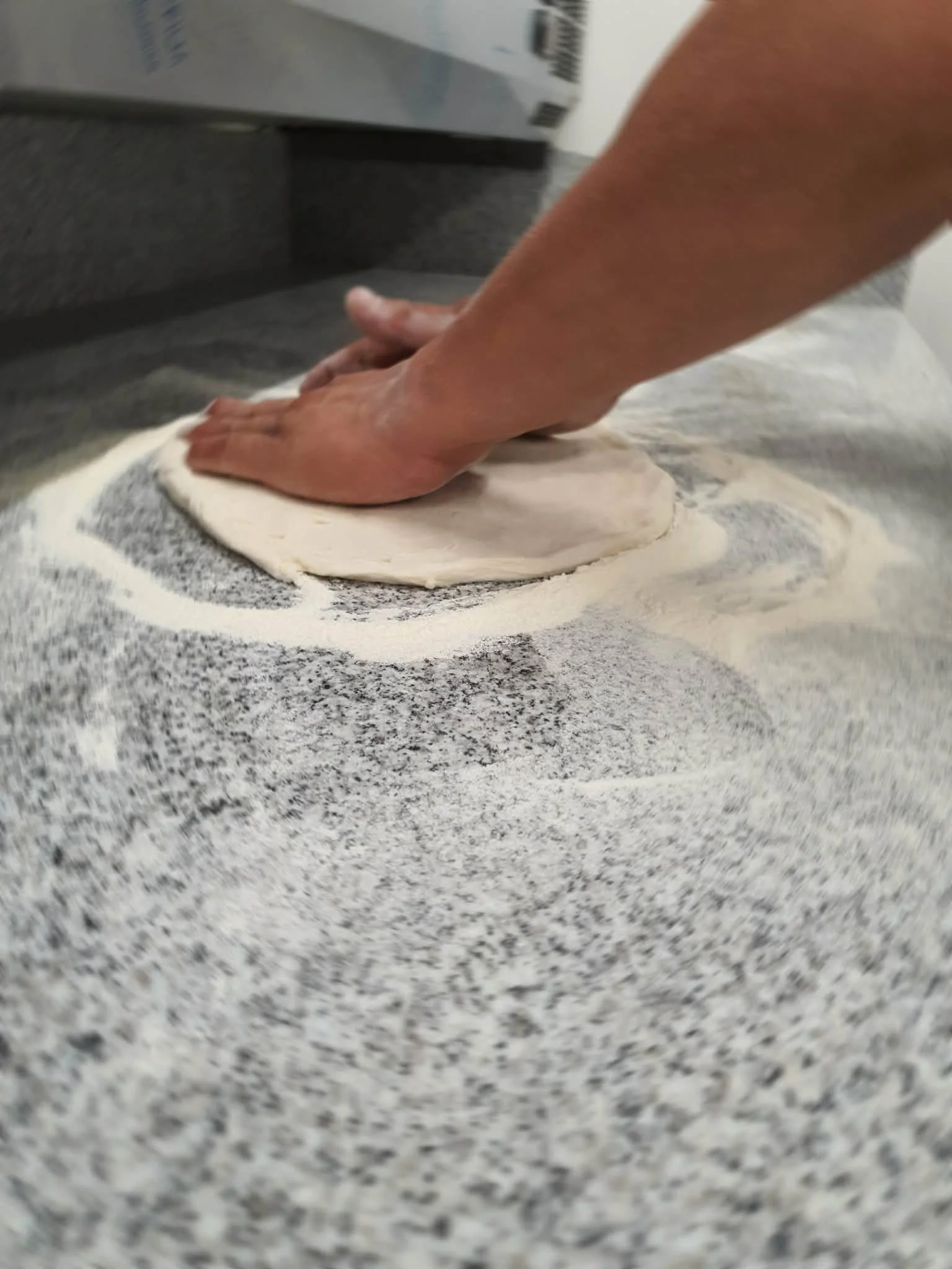 Person rolling out dough on a floured surface.