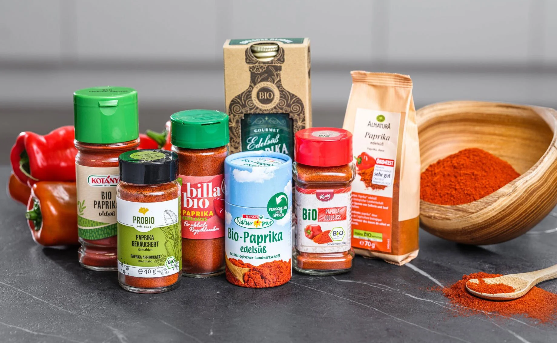 Verschiedene Gewürze und Paprika in Packungen und Gläsern, Paprikaschote, Holzschale mit Paprikapulver, Salz, Pfeffer