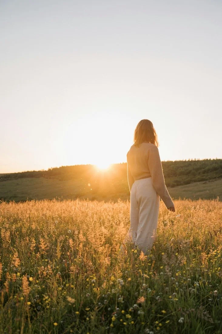 Woman walking through a field at sunset symbolising energy, wellbeing and balanced lifestyle supported by Naturally Nourished Nutrition Clinical Nutritionist Tasmania.