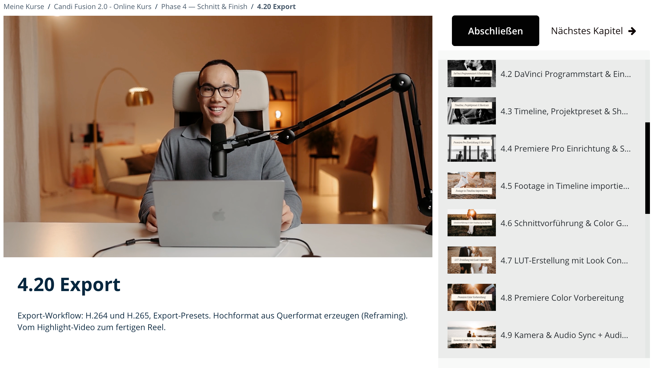 Ein junger Mann mit Brille sitzt an einem Tisch vor einem Laptop, professionell geschminkt, lächelnd und spricht in ein Mikrofon, während er in einem gemütlichen Raum mit warmem Licht und moderner Dekoration arbeitet.