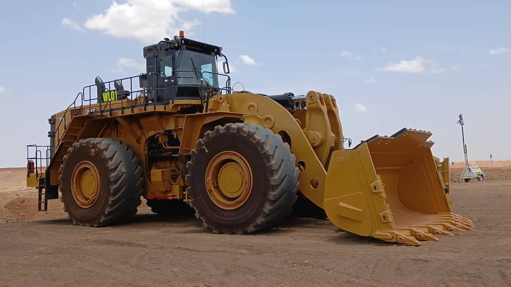 A large yellow bulldozer working on a construction site under a blue sky.