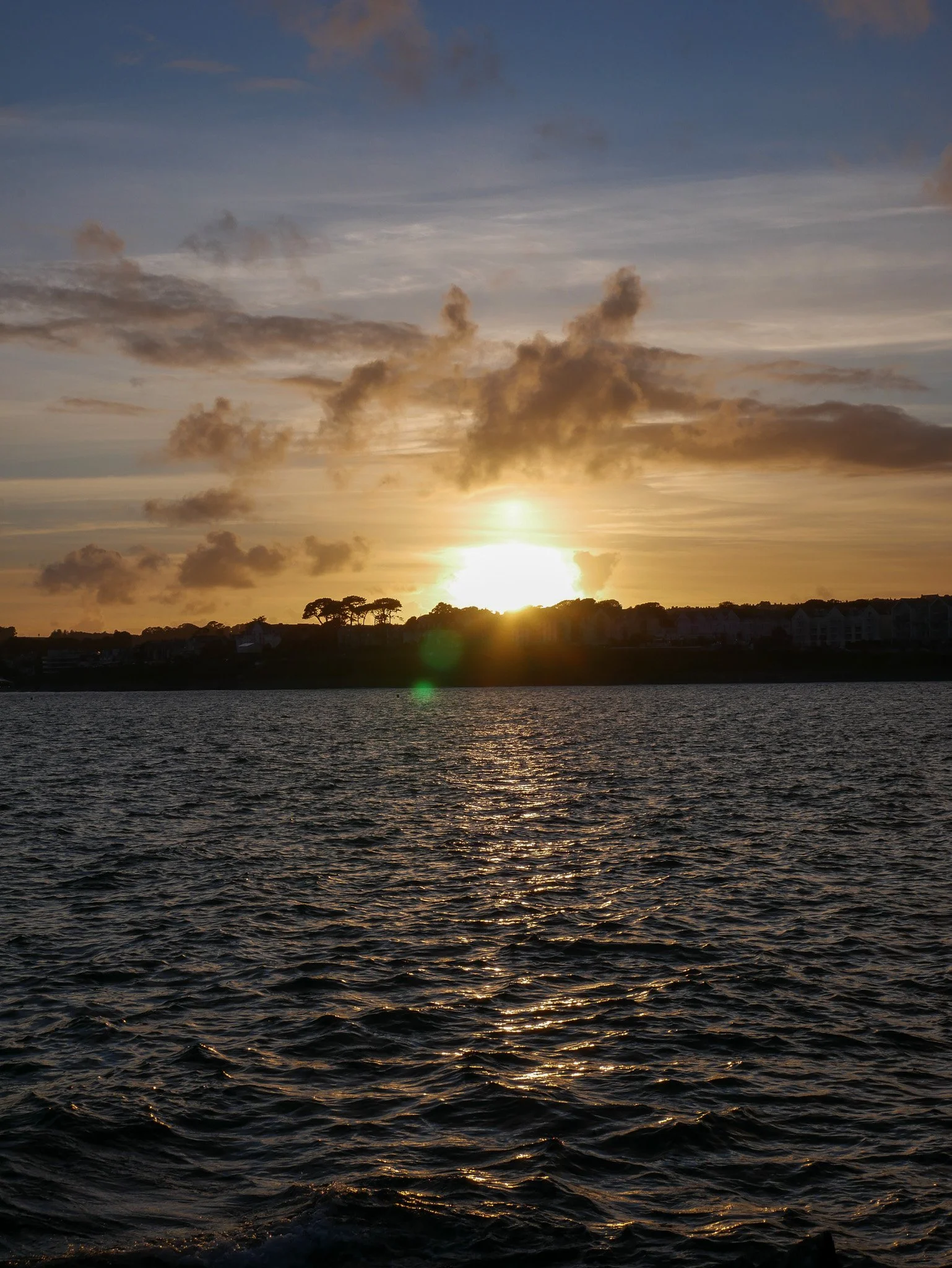 Golden sunset reflecting across water with clouds breaking light