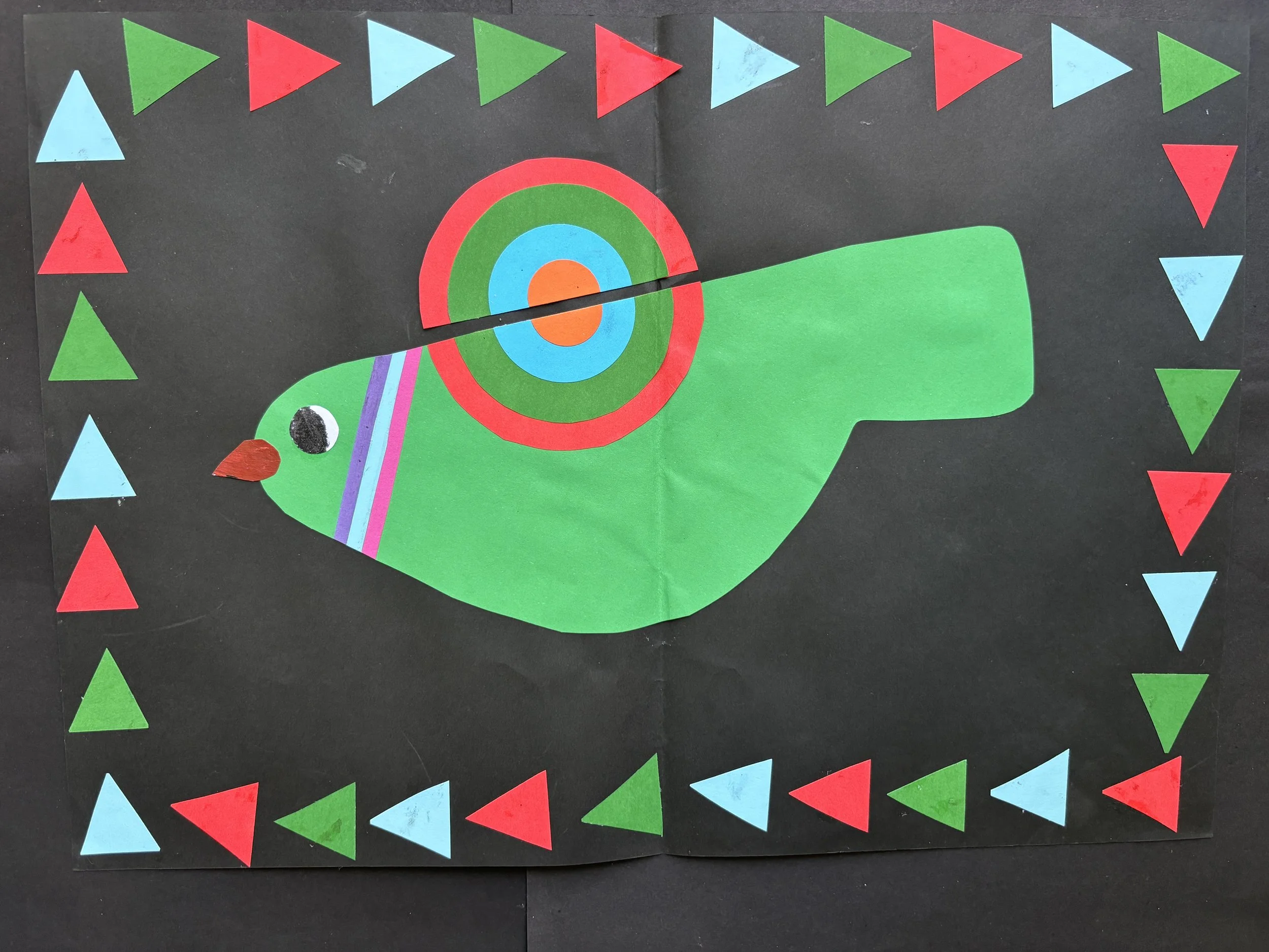 Colorful paper collage of a bird with a rainbow-patterned tail, on a black background with a border of red, green, and blue triangles.
