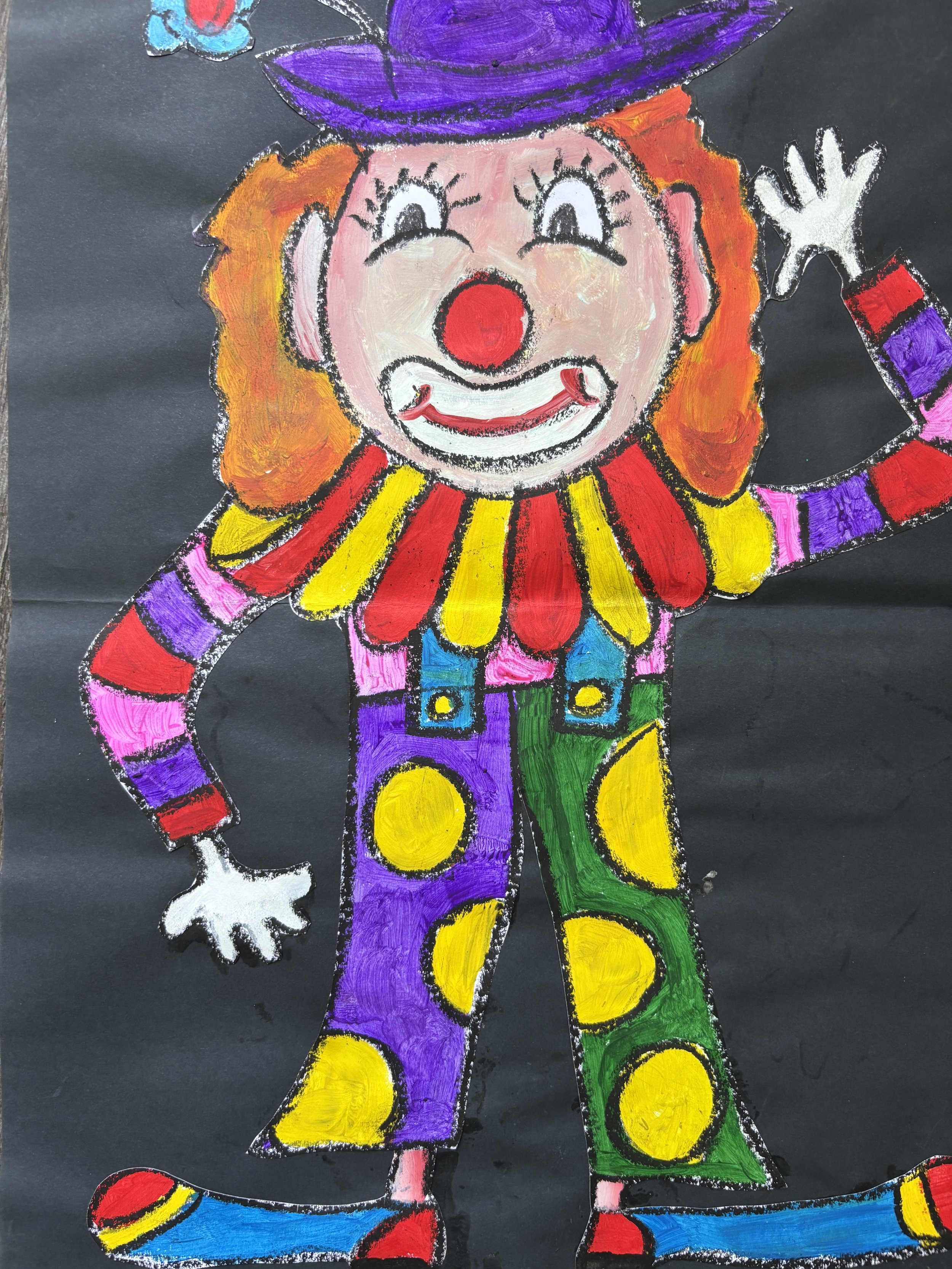 Colorful chalk drawing of a clown with orange hair, a purple hat, red nose, and a big smile, wearing a multicolored polka-dotted outfit and standing on a black background.