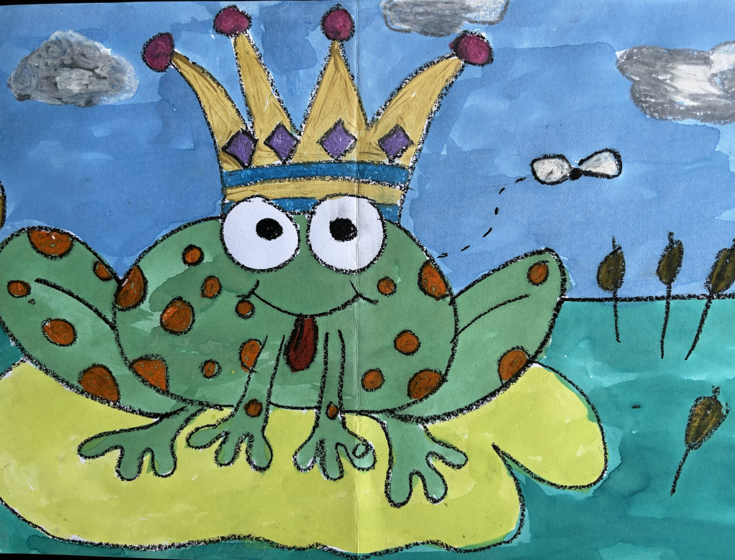 A colorful children's drawing of a frog with butterfly wings wearing a crown, sitting on a lily pad in a pond with cattails and a blue sky with clouds. A small bee is flying nearby.