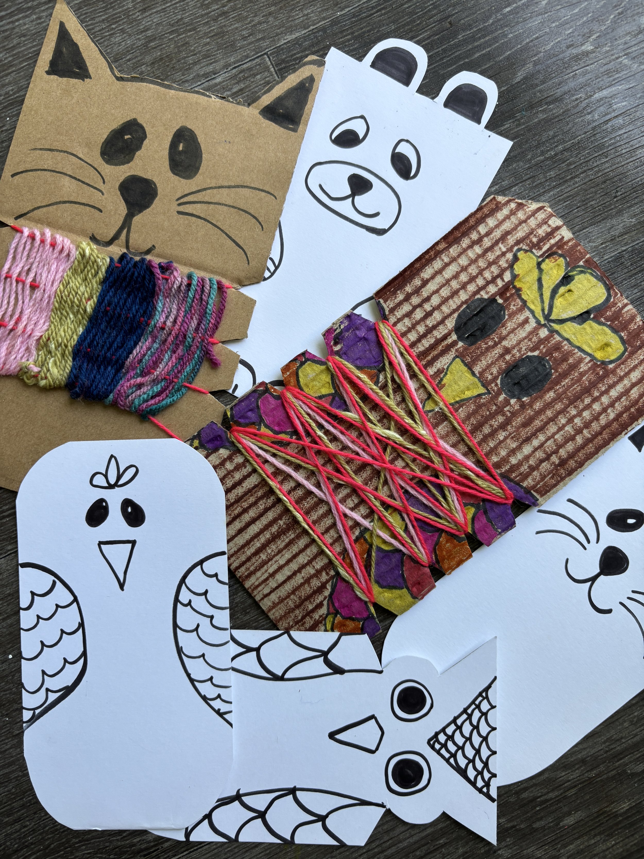 Collection of handmade paper craft animals, including a cat, a bear, a bunny, a butterfly, and a bird, with colorful yarn and embroidery.