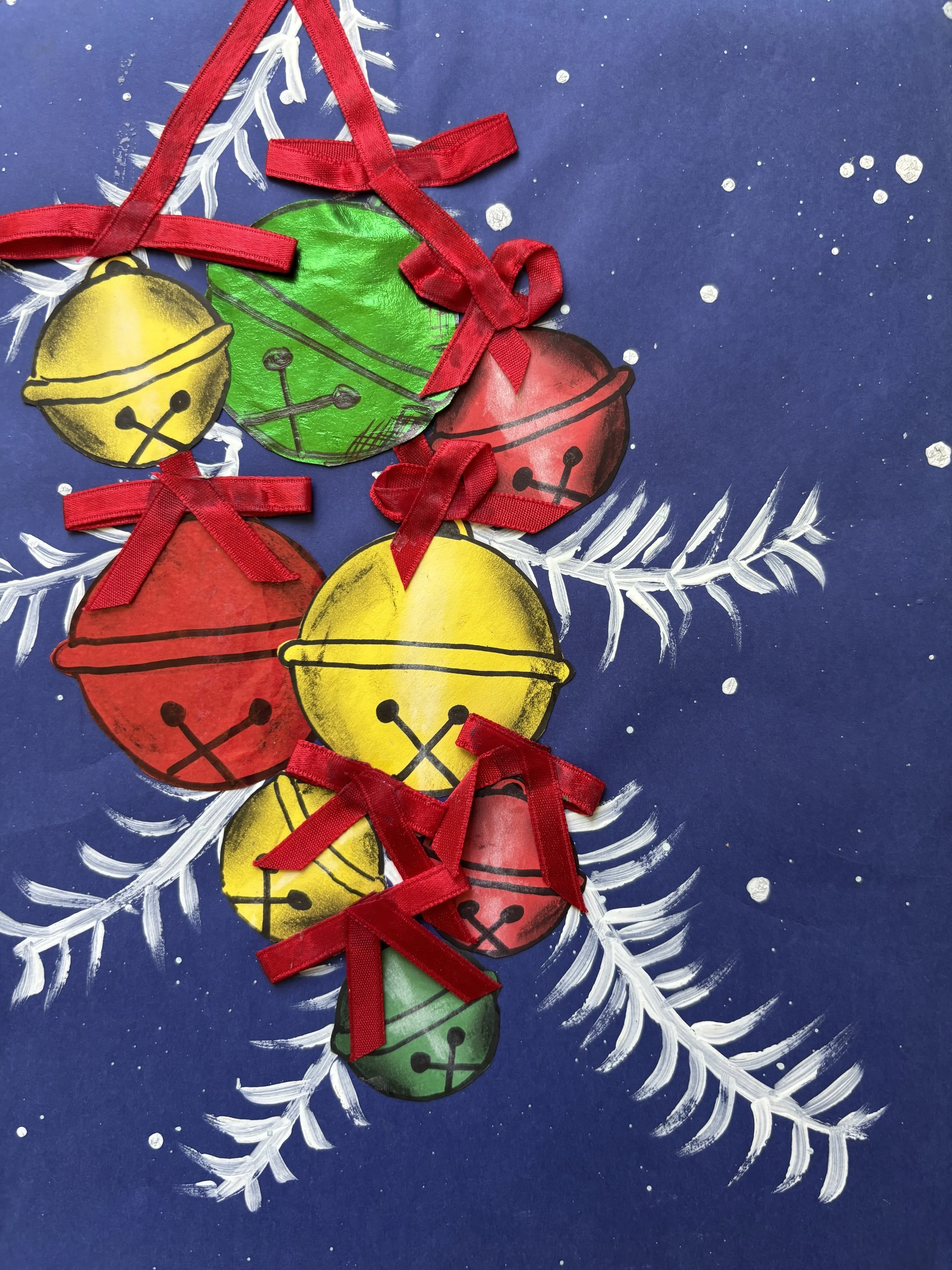 Colorful paper Christmas ornaments with red ribbon bows are arranged on a painted blue background with white snowflakes and a white pine branch.