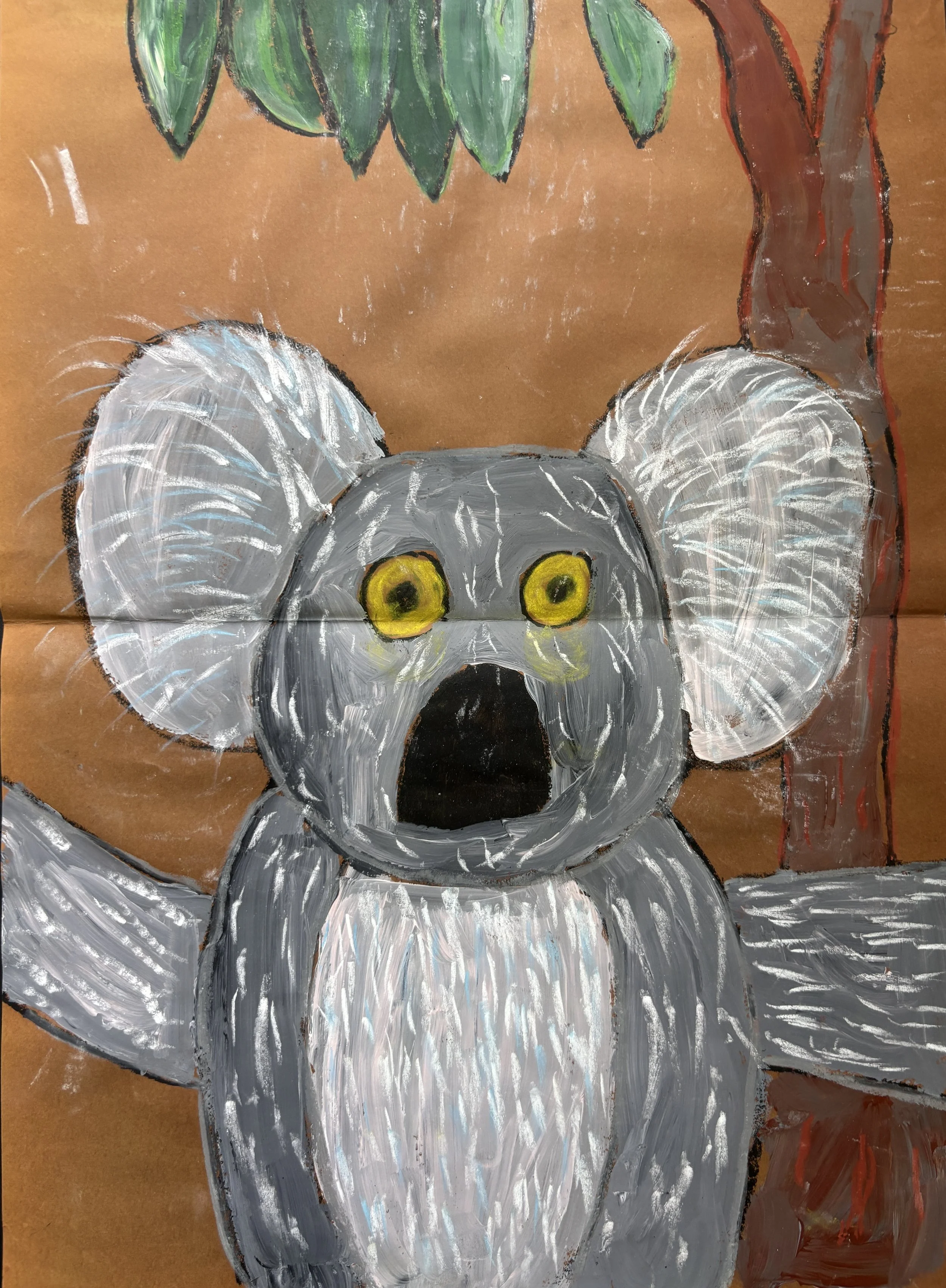 Childs drawing of a surprised koala bear with yellow eyes, gray fur, large ears with white fur, on a brown background with green leaves and a tree trunk.