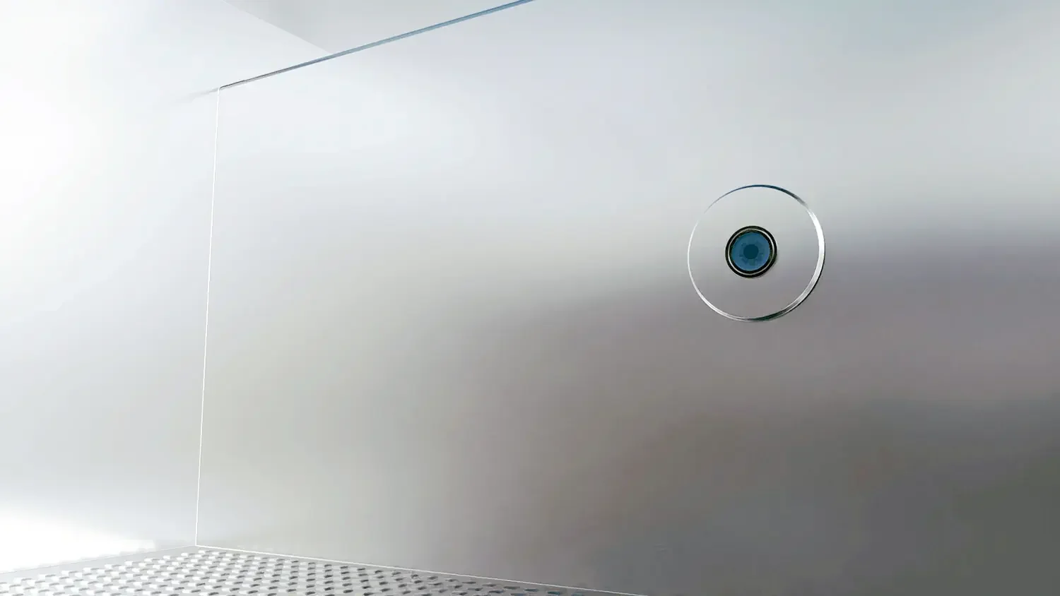 Close-up of a metallic wall with a circular camera or sensor embedded in it.