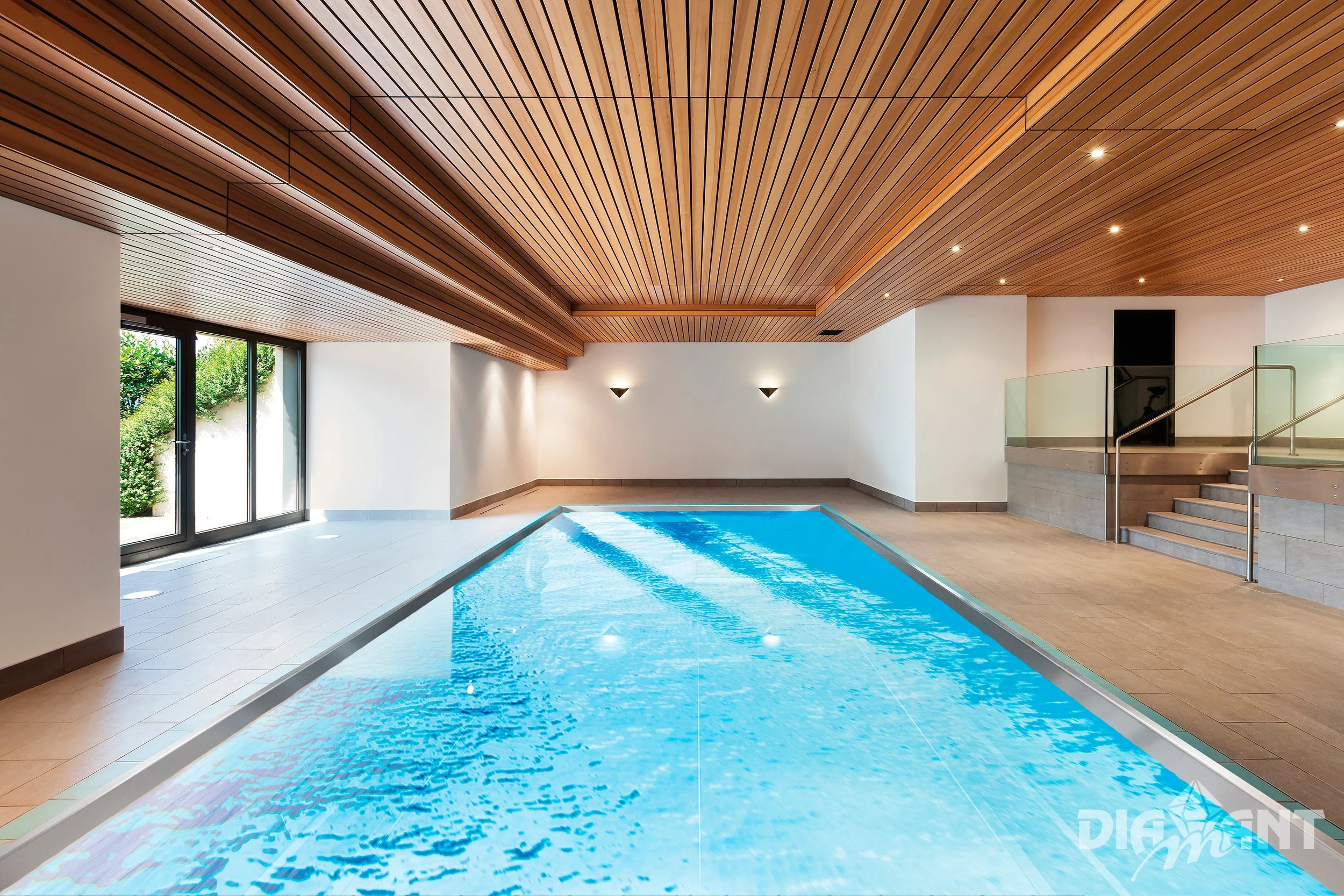 Indoor swimming pool with wooden ceiling, sliding glass doors, tiled floor, and stairway with glass railing