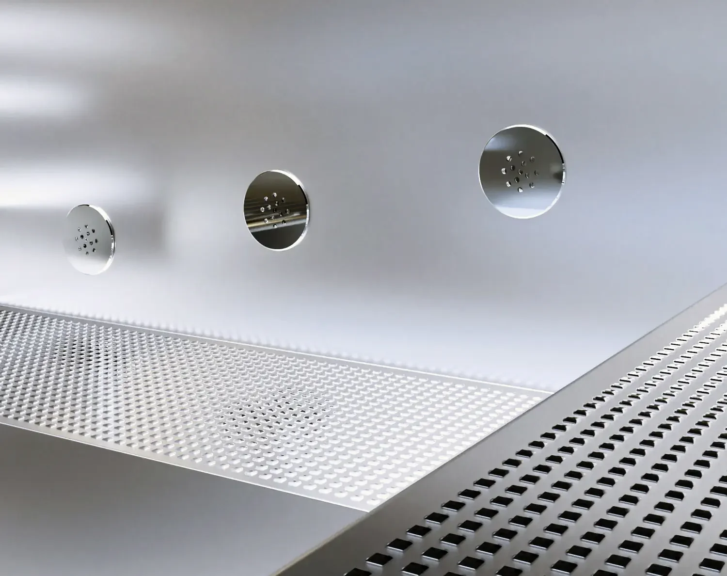 Close-up of a stainless steel industrial or commercial appliance with three circular vents and a perforated surface.
