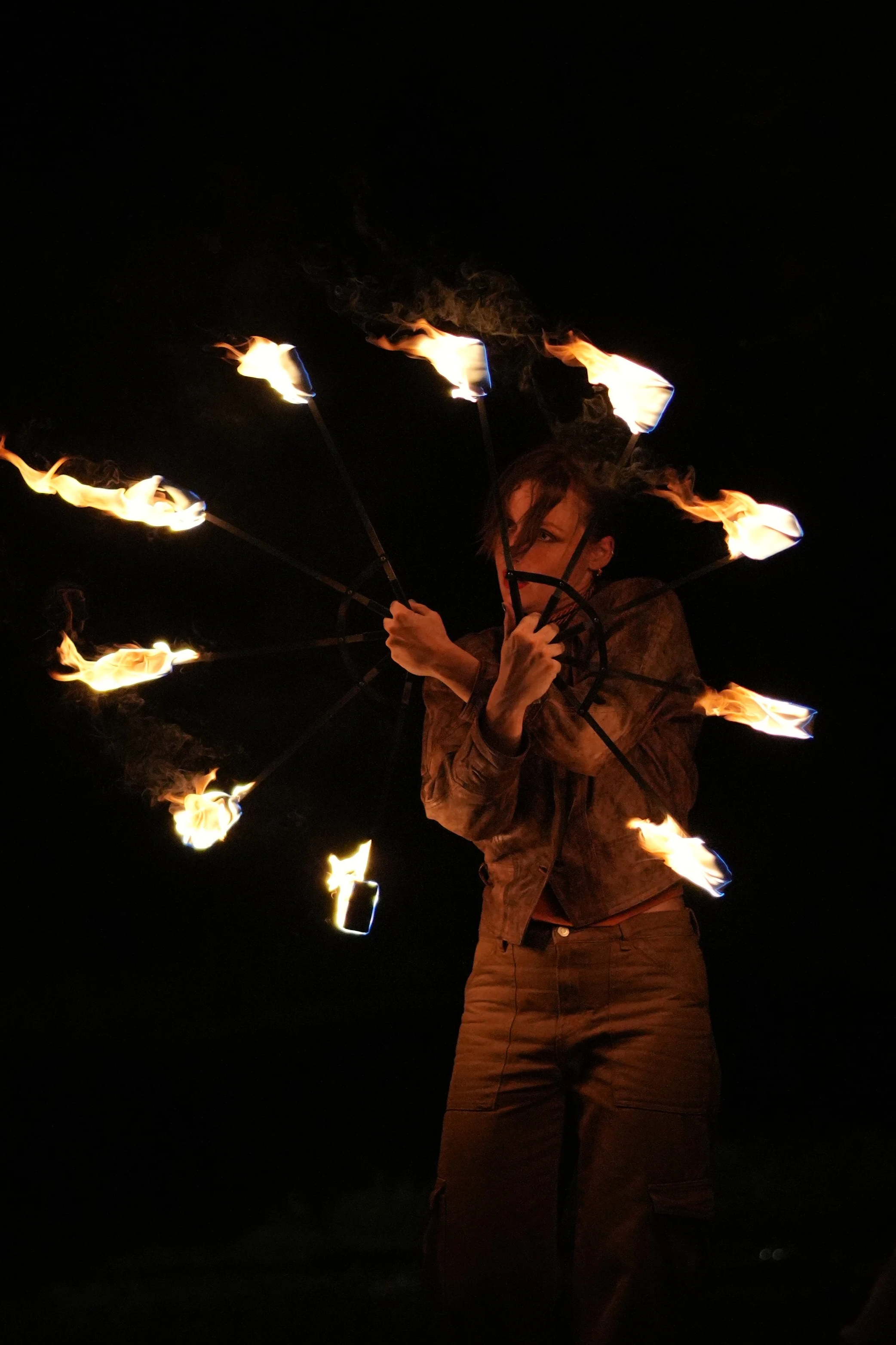 Une personne tient un yawp avec des flammes allumées sur les extrémités dans l'obscurité.