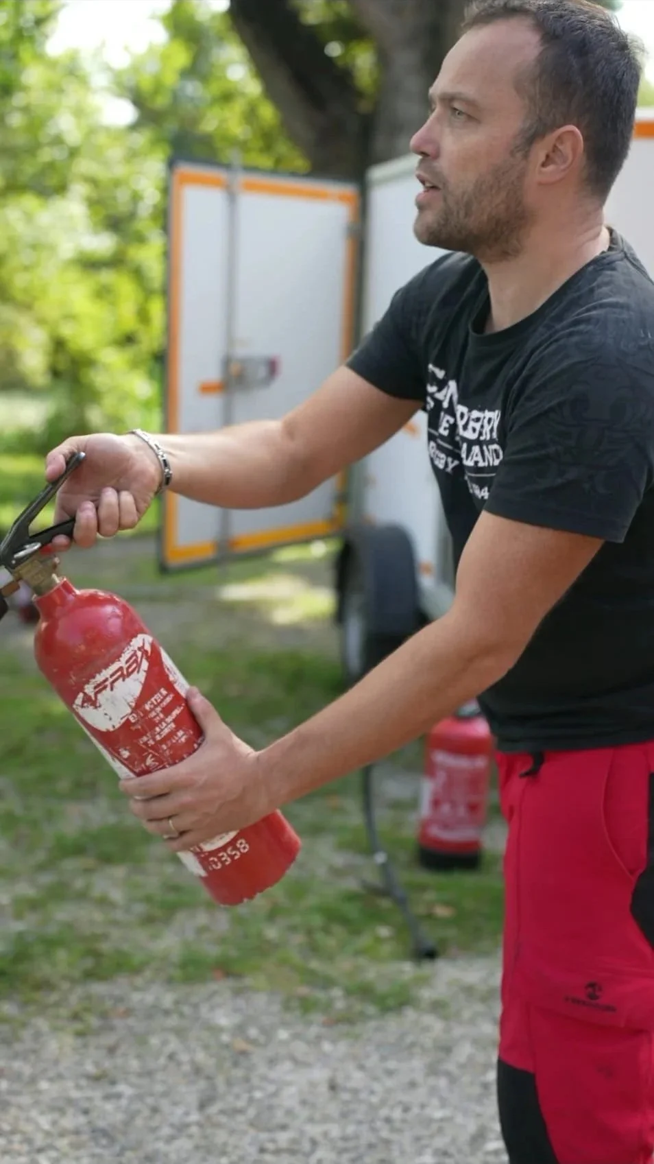 Un homme tenant un extincteur rouge lors d'une démonstration à l'extérieur