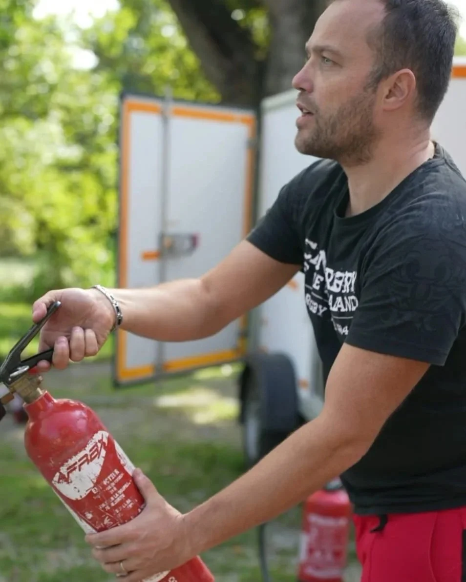 Un homme chargeant une bouteille d'extincteur au feu en extérieur