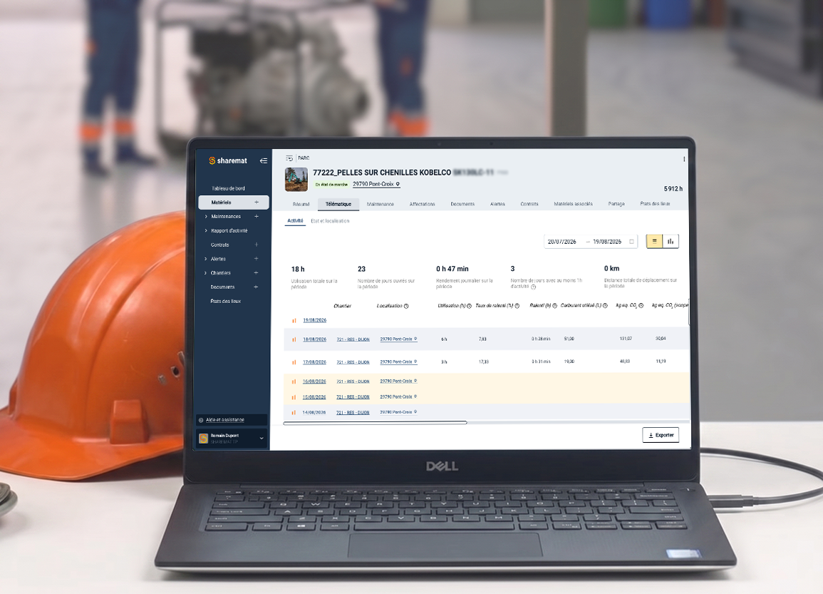 L'écran d'un ordinateur portable Dell affichant une plateforme de gestion de maintenance, à côté d'un casque de sécurité orange, dans un environnement d'atelier ou de chantier.