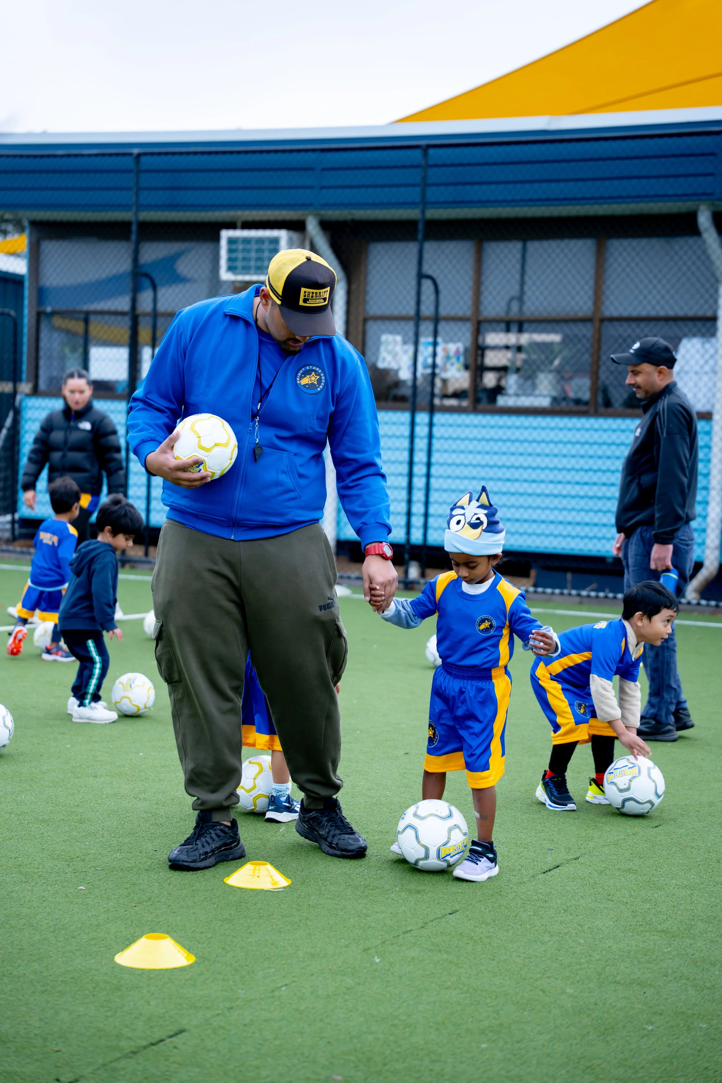 Children participating in a soccer practice on a green field, with coaches supervising