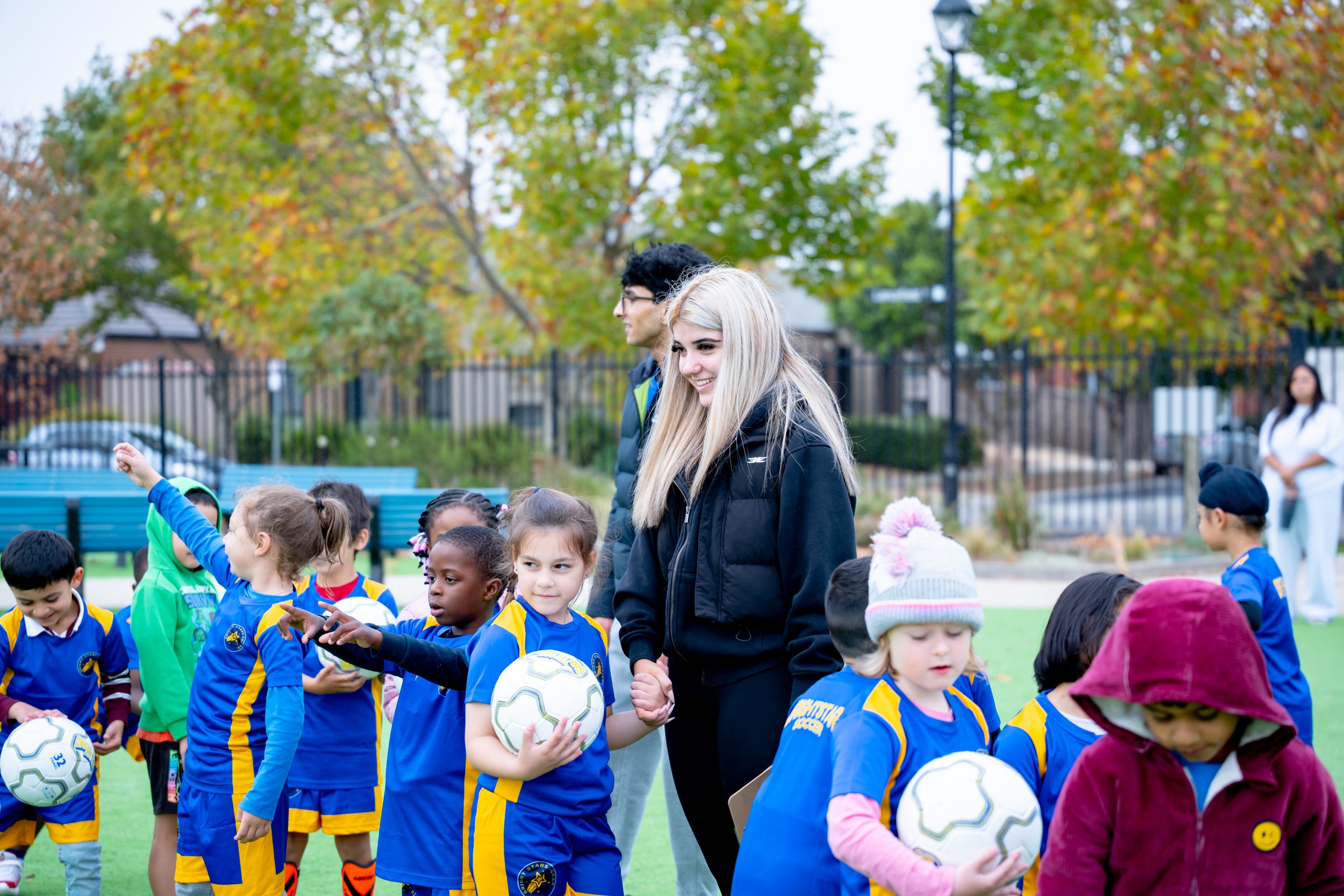 Children in blue and yellow soccer uniforms holding soccer balls after a game or practice